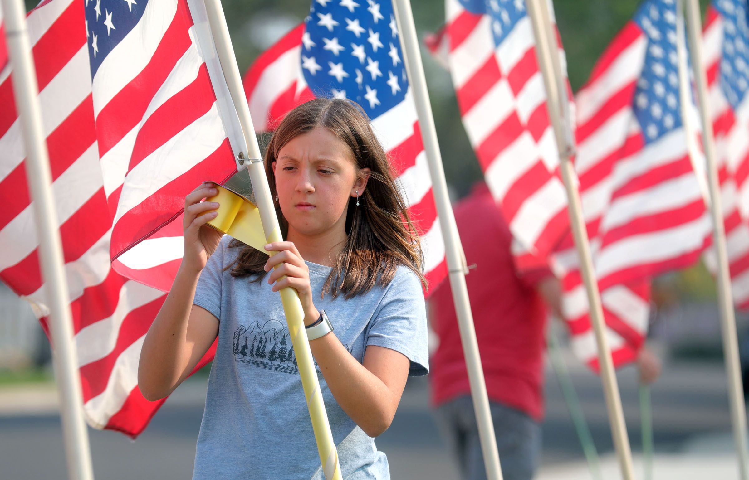 Neighbor Cora McIllece puts up flags around the house belonging to the father of U.S. Marine Staff Sgt. Darin Taylor Hoover Jr. in Sandy on Aug. 27, 2021. Hoover Jr. was killed in the suicide bombing at the Kabul Airport in Afghanistan.