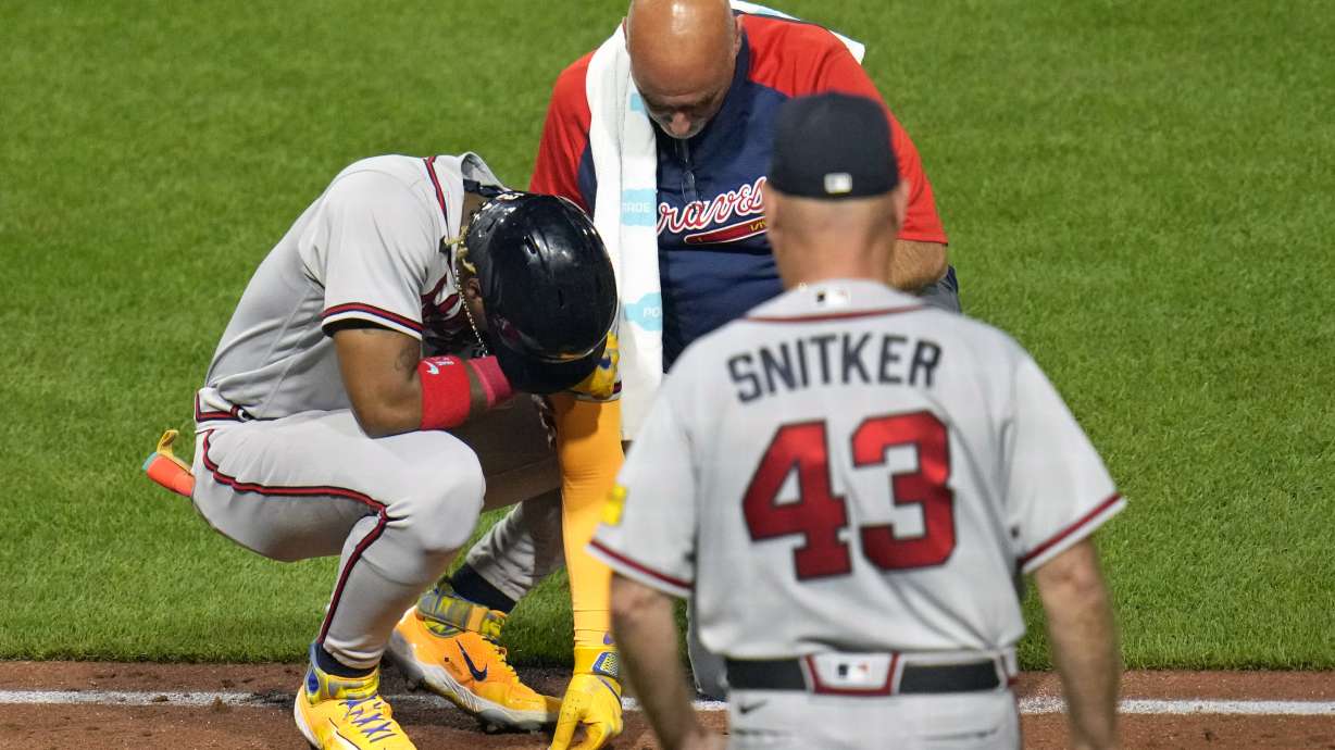Atlanta Braves' Ronald Acuña Jr., left, is checked by a team trainer and manager Brian Snitker (43) after being hit by a pitch from Pittsburgh Pirates' Colin Holderman during the sixth inning of a baseball game in Pittsburgh, Tuesday, Aug. 8, 2023.