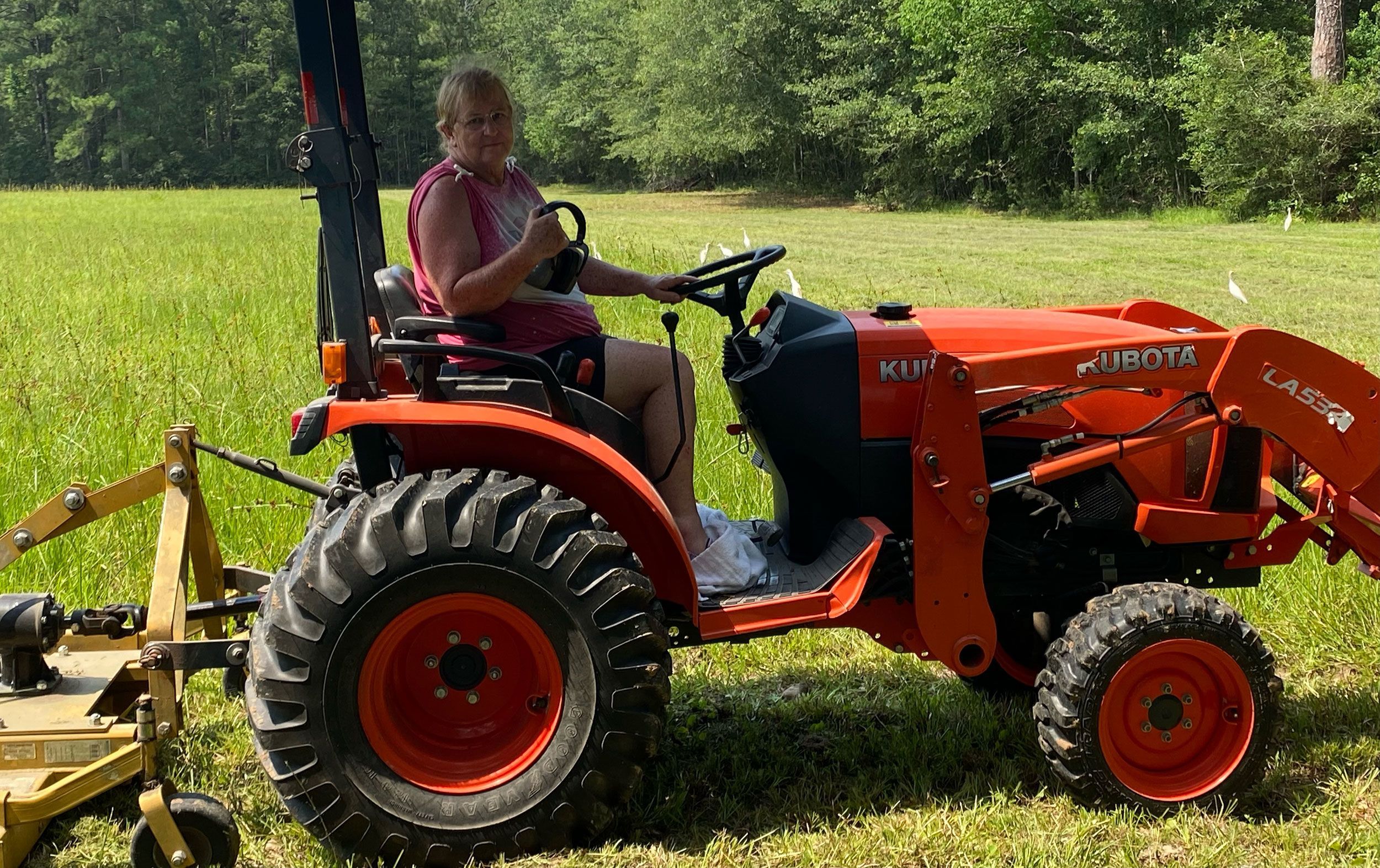 Peggy Jones sits on one of two tractors used to groom her property. She survived a snake and hawk attack while working in her yard in Texas last month.