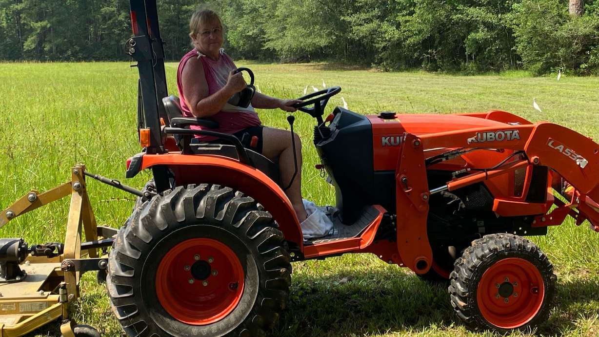 Peggy Jones sits on one of two tractors used to groom her property. She survived a snake and hawk attack while working in her yard in Texas last month.