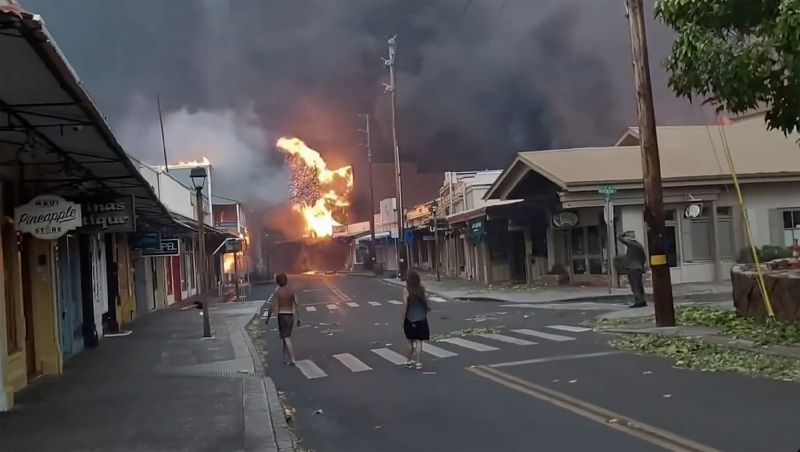 People watch as smoke and flames fill the air from raging wildfires on Front Street in downtown Lahaina, Maui on Tuesday. Maui officials say a wildfire in the historic town has burned parts of one of the most popular tourist areas in Hawaii.