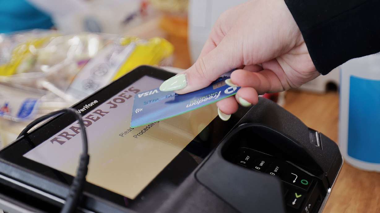 A woman uses her card to make her purchase at Trader Joe’s in Draper on March 3. U.S. consumer credit card debt rose nearly 5% in the second quarter of 2023.