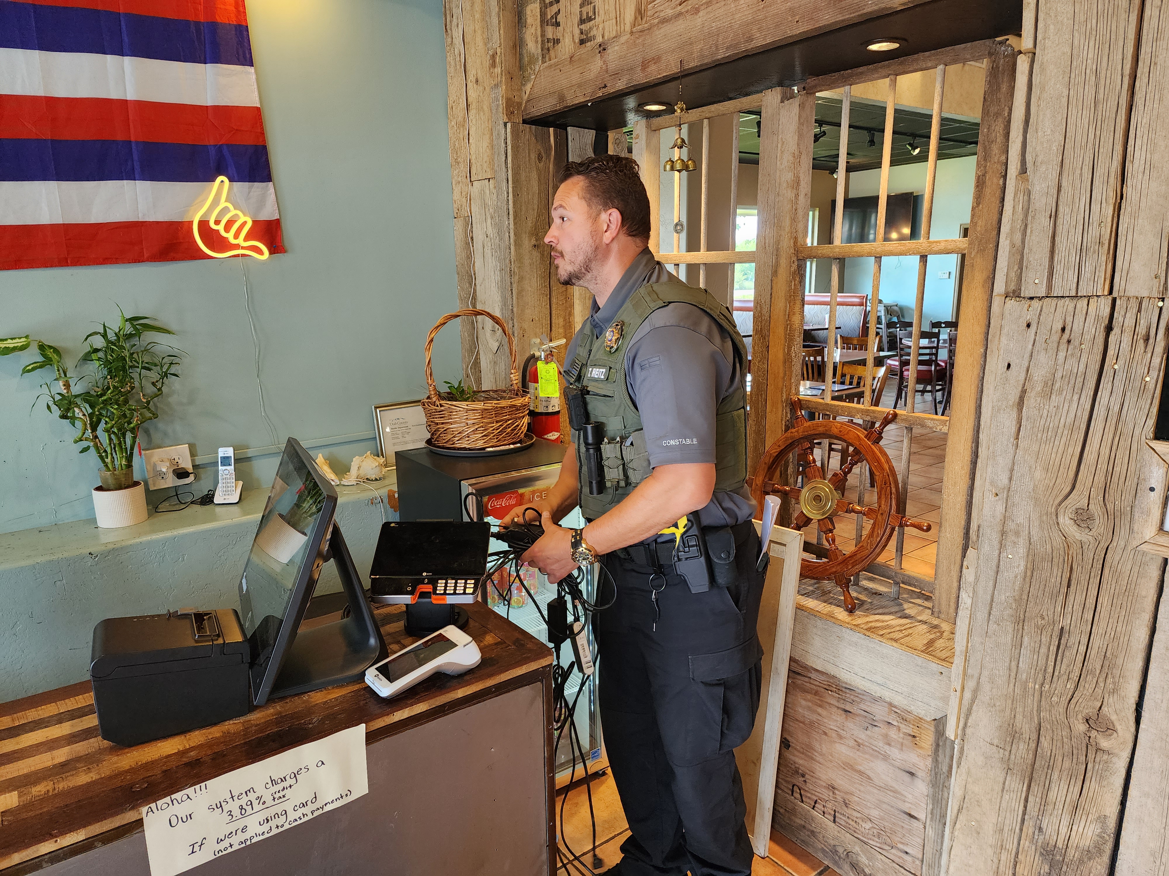 Constable Travis Reitz takes the credit card terminals at a Lindon restaurant, as part of a writ of execution he served in late July.