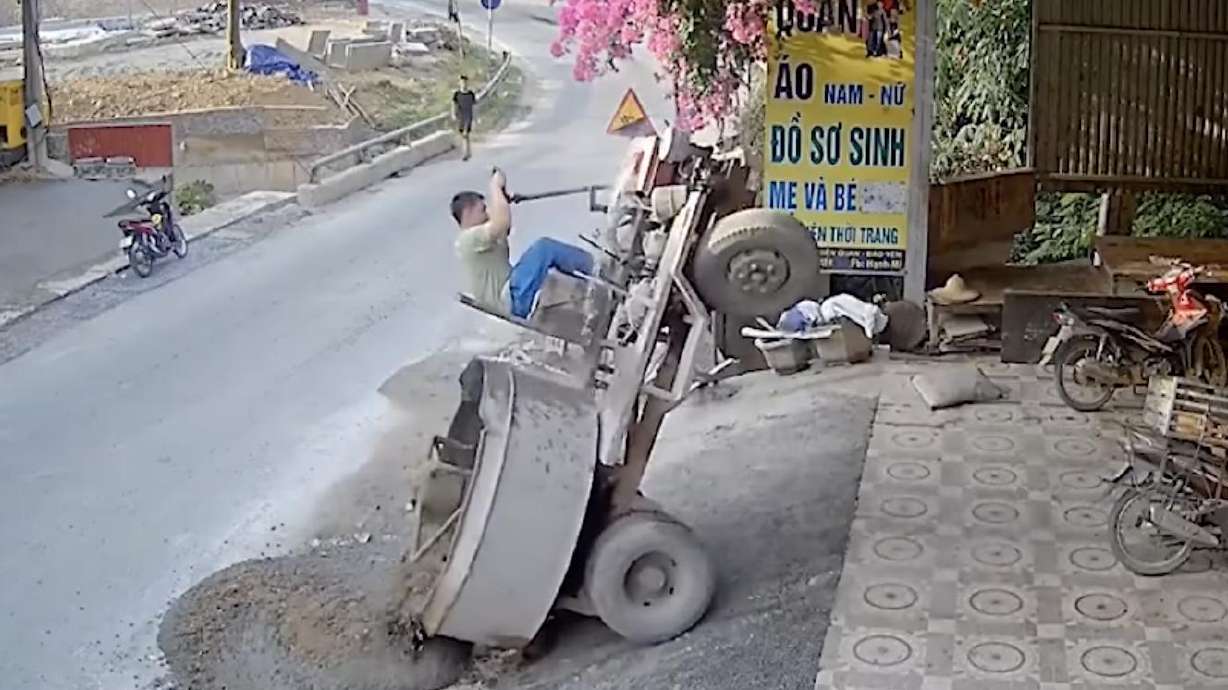 The driver of a cement truck in Dien Quan, Bao Yen, Lao Cai, Vietnam, finds himself in a precarious position in early July.