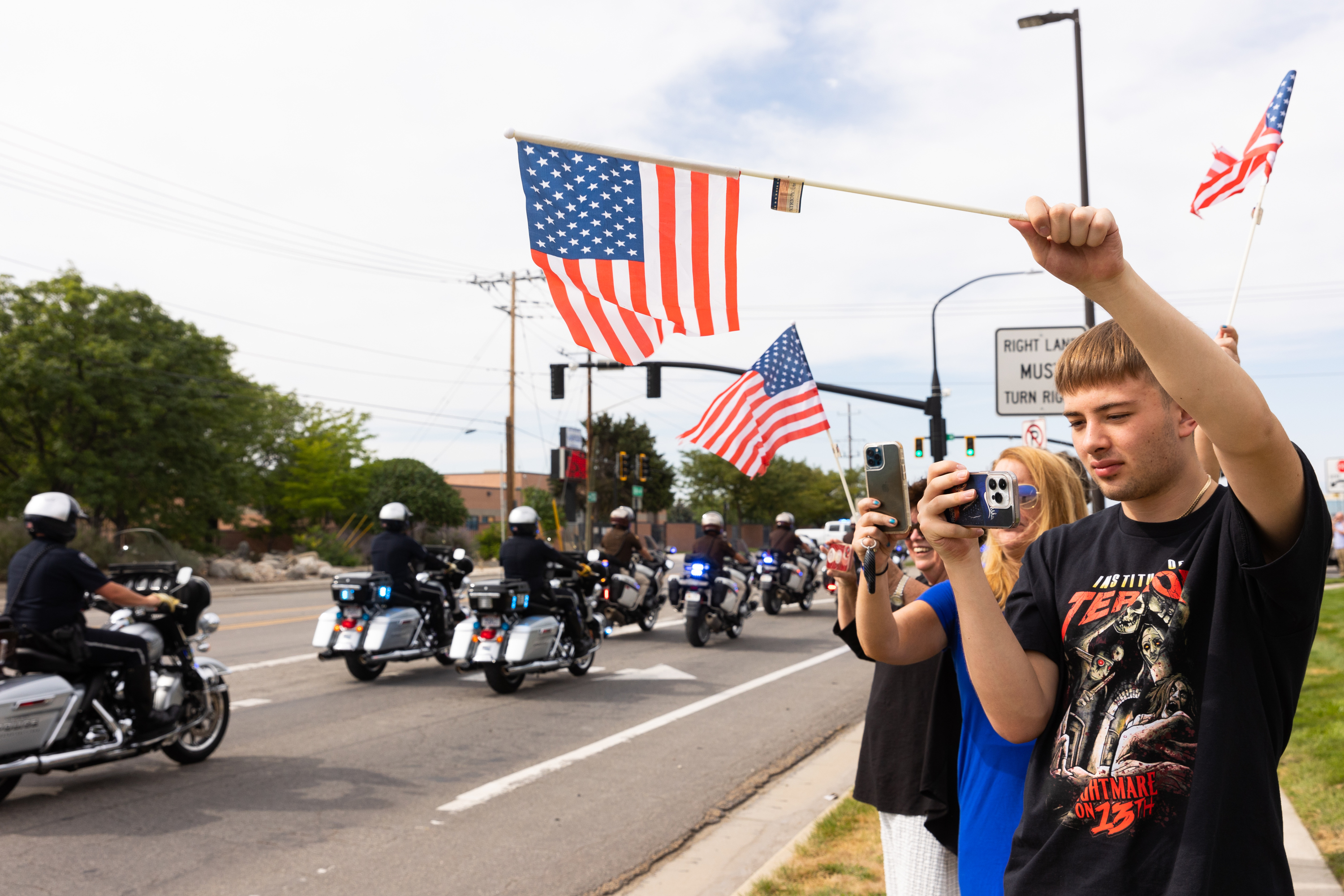 Michael Furgis watches with his mom Susanne Gustin as the presidential motorcade drives out of the Roland R. Wright Air National Guard Base in Salt Lake City on Wednesday.