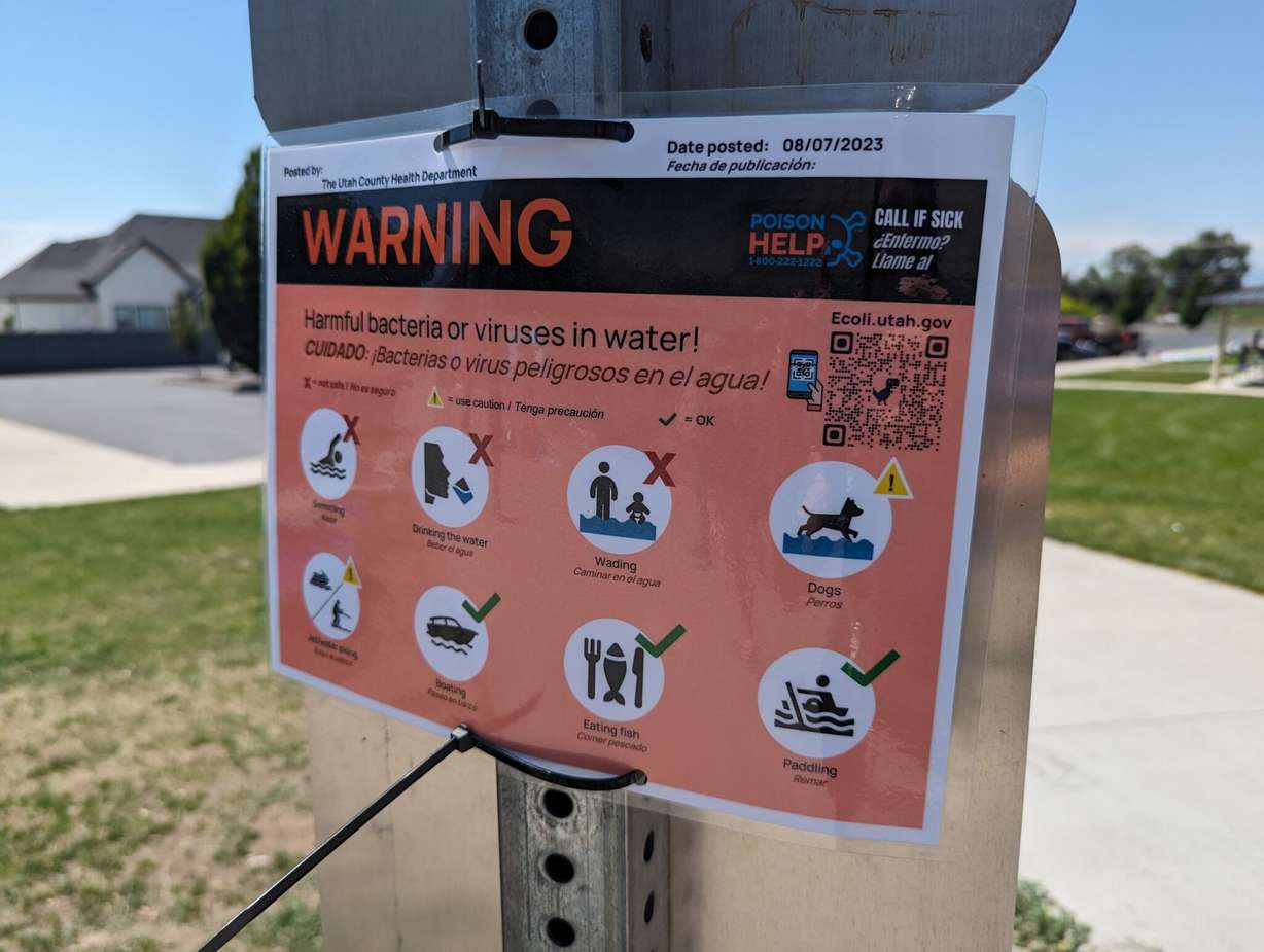It’s hard to spot the E. coli warning sign, which is posted on the back of other signs at Manila Creek Pond in Pleasant Grove. Families say poor signage is not giving swimmers the warning that a health advisory has been issued for the pond.