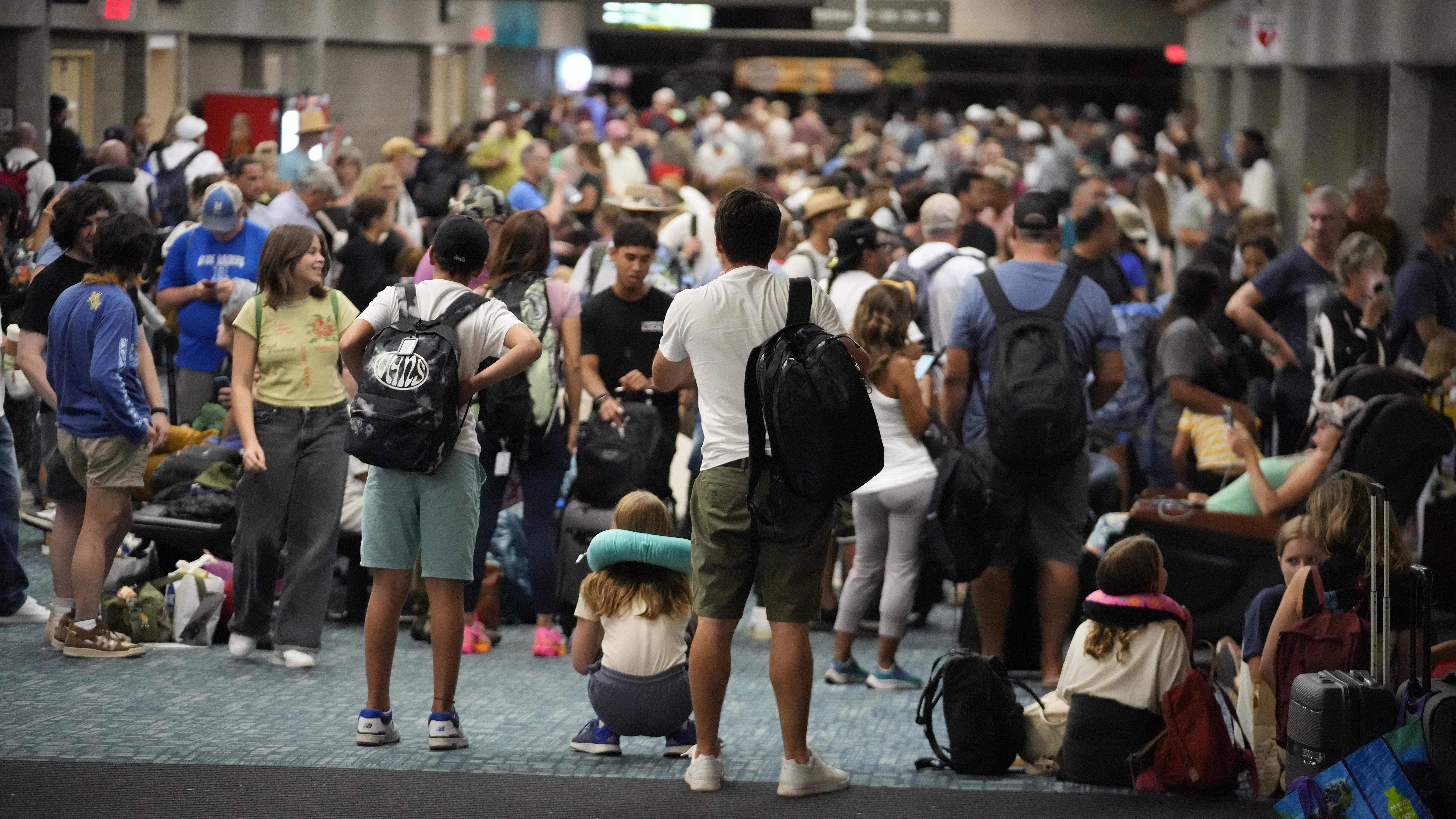 People gather at the Kahului Airport while waiting for flights Wednesday, in Kahului, Hawaii. Several thousand Hawaii residents raced to escape homes on Maui as the Lahaina fire swept across the island, killing multiple people and burning parts of a centuries-old town.
