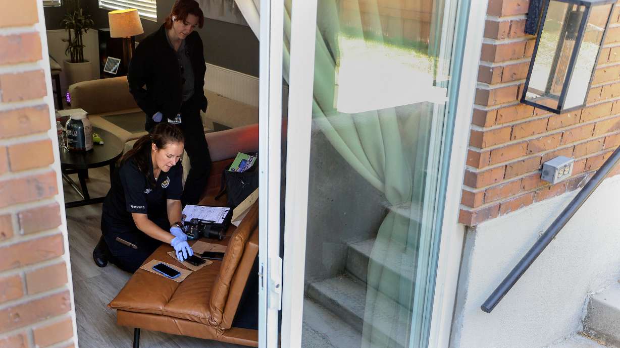 Unified police investigator Nicole Garrett documents evidence during a home search after two people were taken into custody in an odometer scam in South Salt Lake on Wednesday. Unified police technical services secretary Abby Reynolds watches.