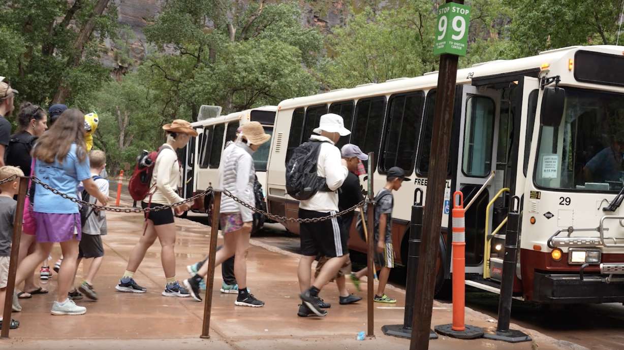 Zion National Park visitors walk through the rain to a shuttle bus by the Temple of Sinawava on Aug. 2. Flash flooding is possible at the park for at least the next two days.
