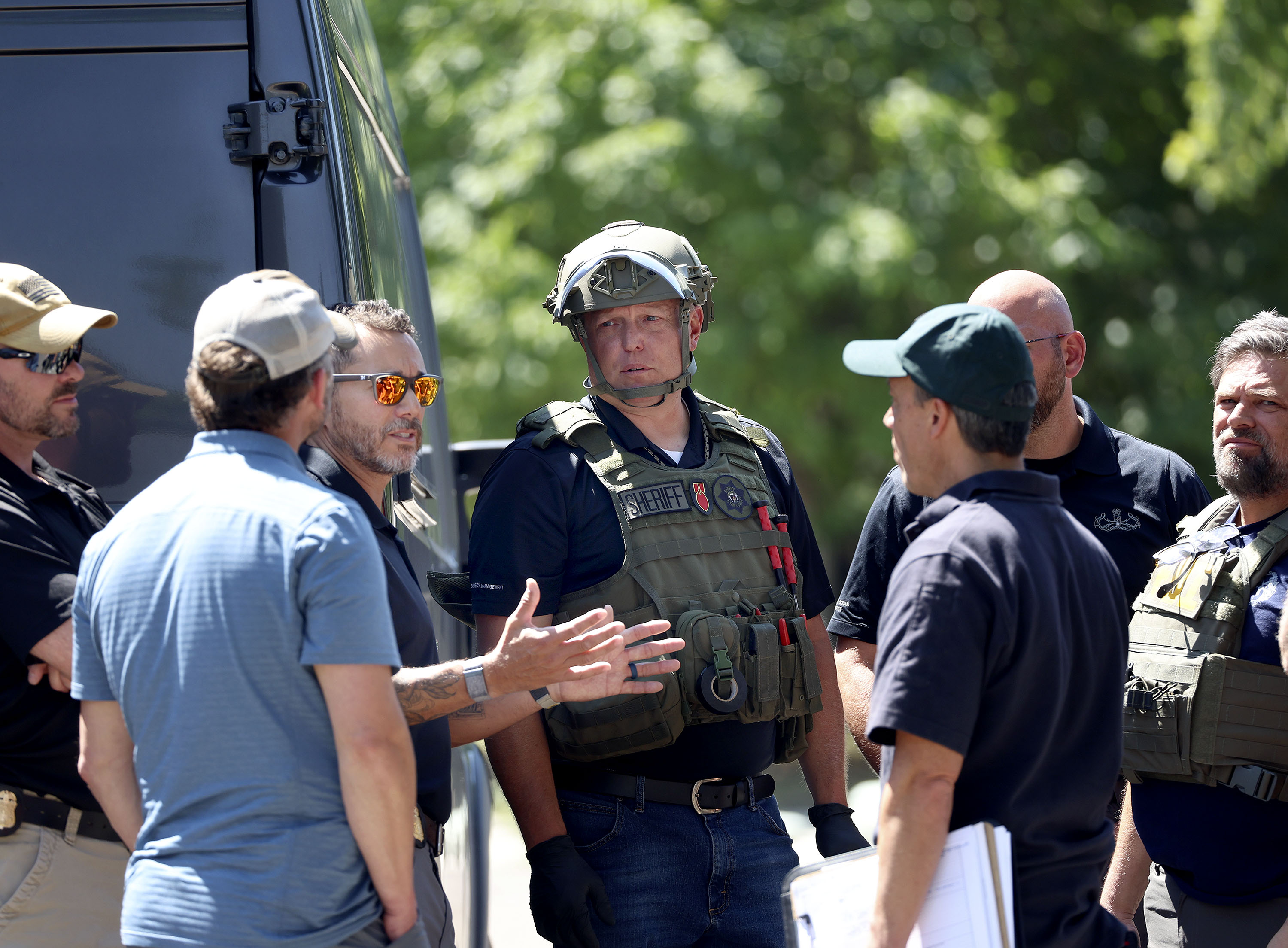 Law enforcement agents confer at the home of Craig Deeleuw Robertson who was shot and killed by FBI agents in Provo on Wednesday. Robertson allegedly posted threatening comments about President Joe Biden hours before the president arrived in Utah.