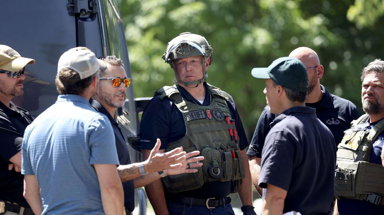 Law enforcement agents confer at the home of Craig Deeleuw Robertson who was shot and killed by FBI agents in Provo on Wednesday. Robertson allegedly posted threatening comments about President Joe Biden hours before the president arrived in Utah.