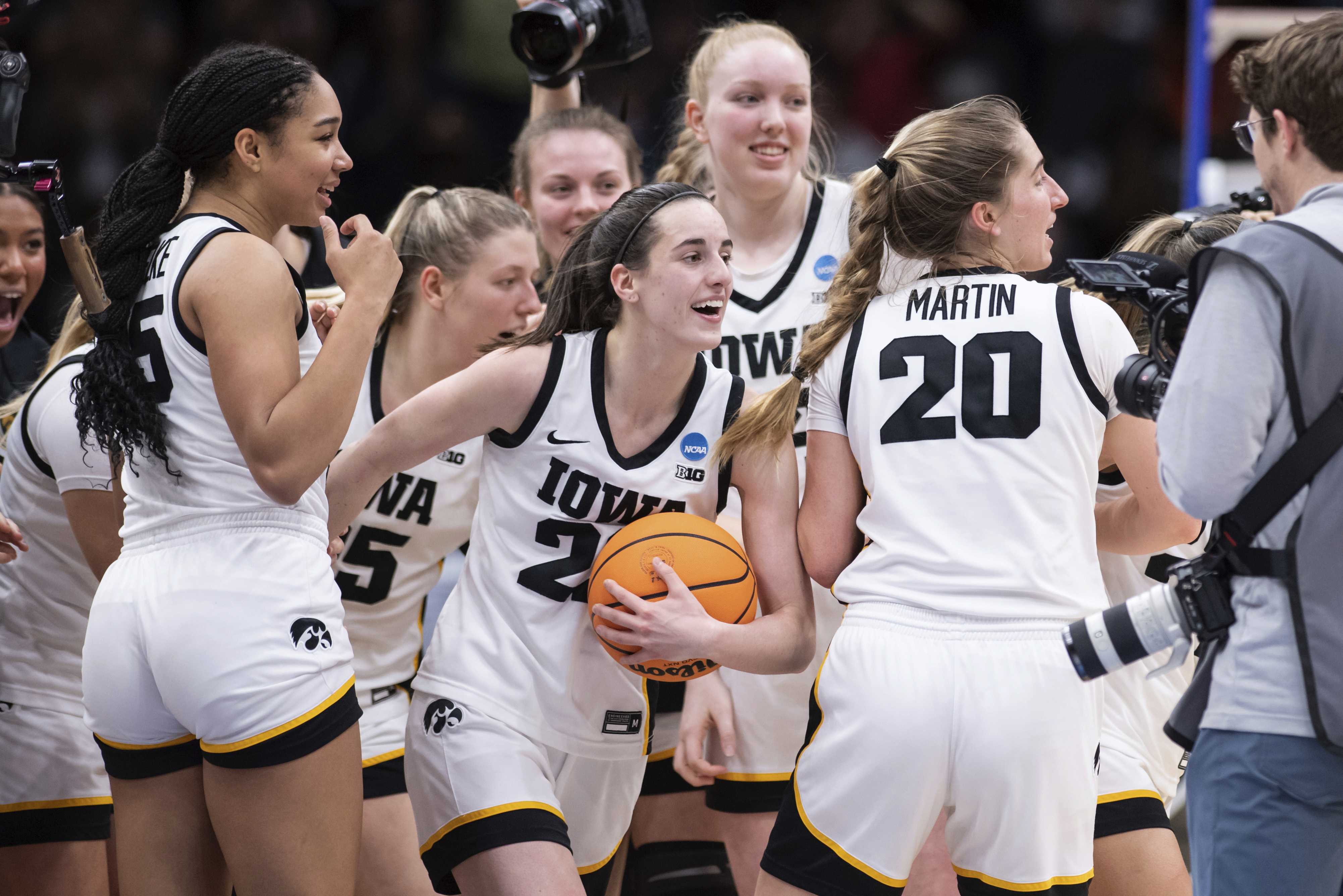 FILE - Iowa players, including guard Caitlin Clark, front center, forward Hannah Stuelke, front left, and guard Kate Martin (20) celebrate after an Elite 8 basketball game of the NCAA Tournament against Louisville, Sunday, March 26, 2023, in Seattle. Iowa will attempt to set the all-time women's basketball attendance record when it hosts DePaul in an outdoor exhibition at 69,000-seat Kinnick Stadium on Oct. 15, the school announced Thursday, Aug. 10, 2023. 