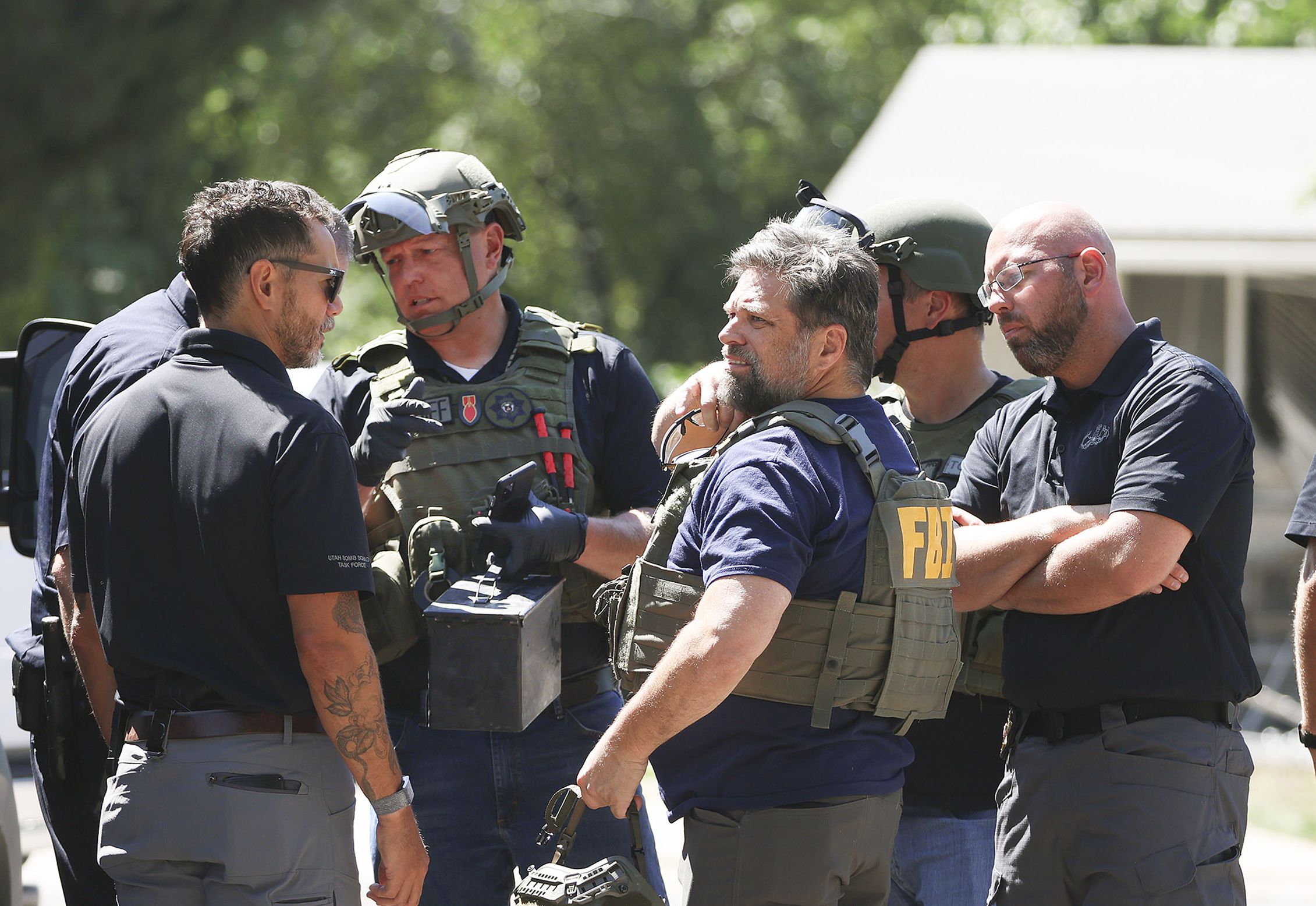 Law enforcement agents confer at the home of Craig Deeleuw Robertson who was shot and killed by FBI agents in Provo on Wednesday. Robertson posted threatening comments about President Joe Biden hours before the president was scheduled to visit Utah.