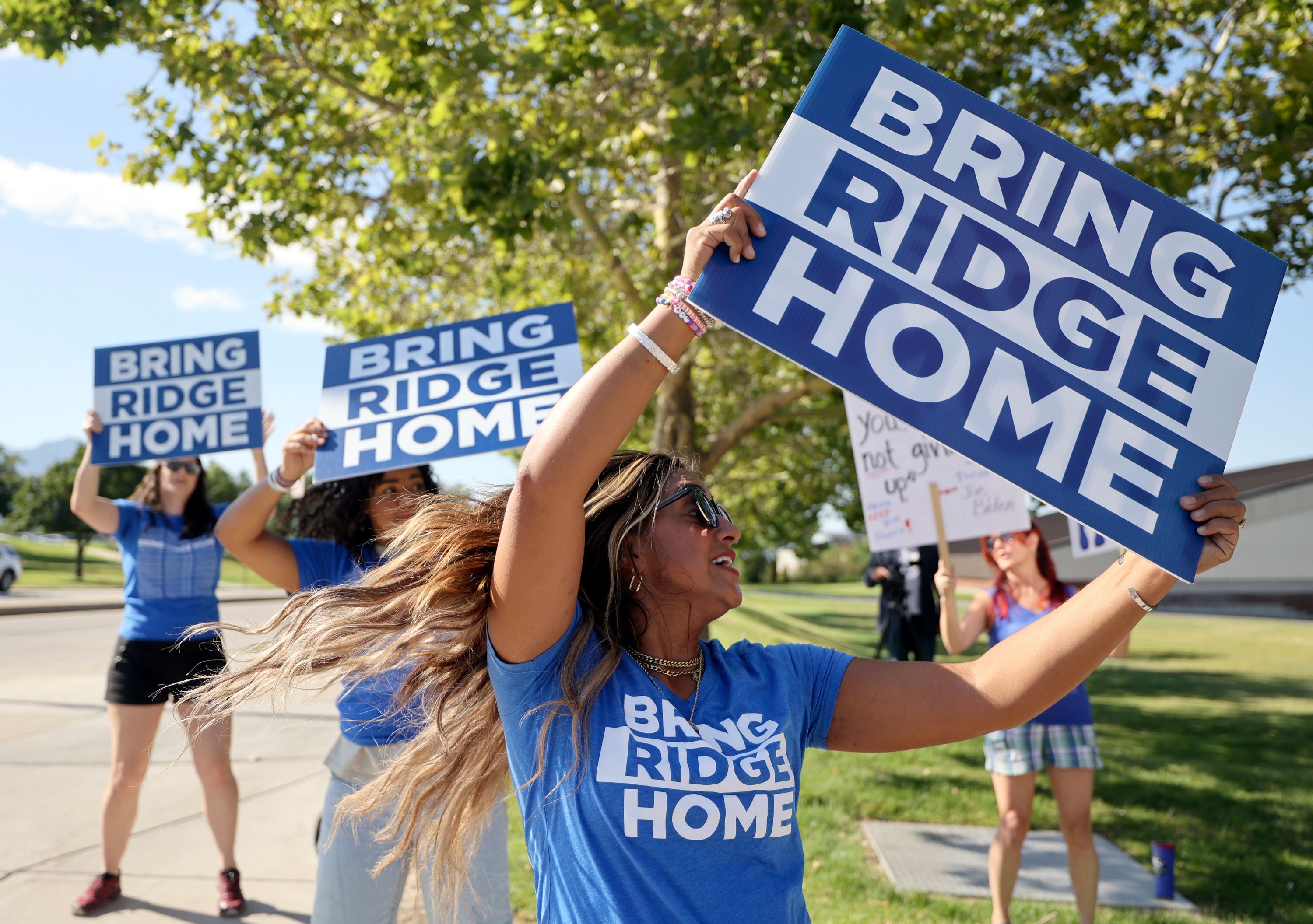 Tia Stokes dances as she holds a “Bring Ridge Home” sign and waits on 500 South for President Joe Biden’s motorcade to pass on the way to the George E. Wahlen Department of Veterans Affairs Medical Center, where he will deliver remarks, in Salt Lake City on Thursday. Stokes is Ridge Alkonis’ cousin.