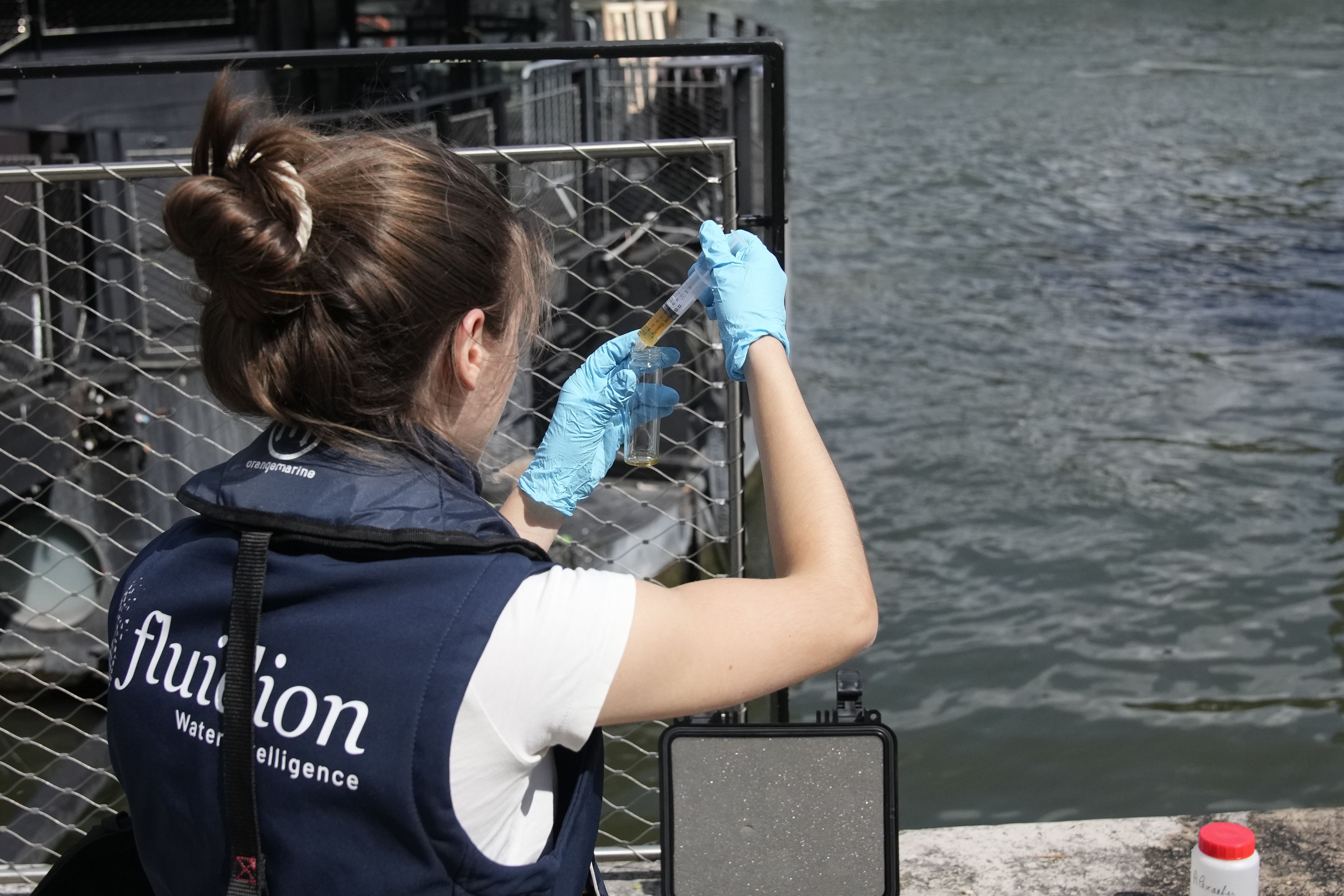Aurelie Lemaire, a microbiology research intern, uses a reagent to test the Seine River water quality, on Aug. 4 in Paris. Heavy rains have set back plans to test Paris’ readiness for swimmers to race in the River Seine at next year’s Summer Olympics.