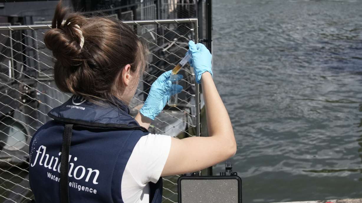 Aurelie Lemaire, a microbiology research intern, uses a reagent to test the Seine River water quality, on Aug. 4 in Paris. Heavy rains have set back plans to test Paris’ readiness for swimmers to race in the River Seine at next year’s Summer Olympics.
