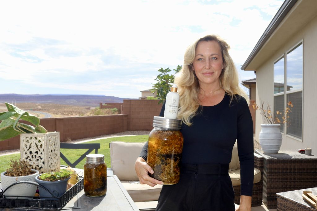 Jenna Stinger holds a bottle of coconut oil infused with Ayurveda herbs, an ingredient she uses in her Desert Goddess Geometry Lotion, in St. George on July 31.