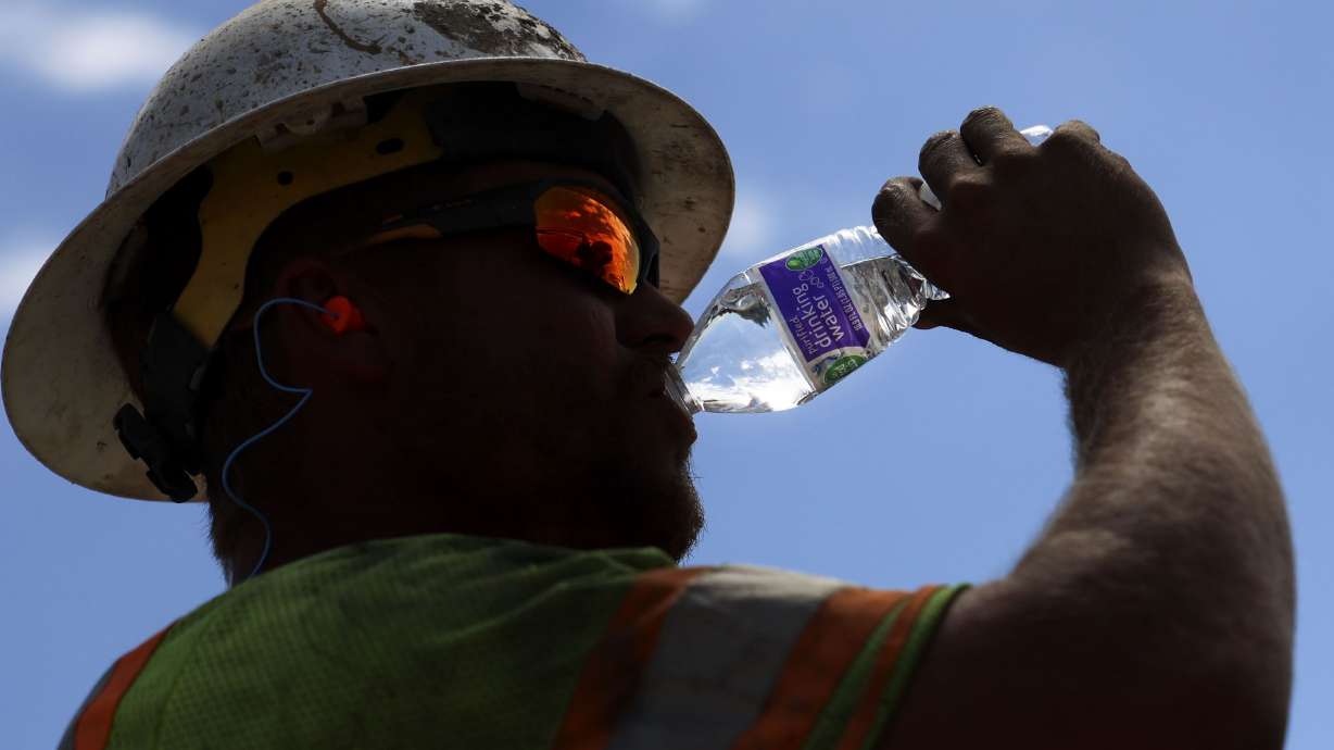 Garrett Rowser hydrates while working on the I-215 renewed reconstruction project in Salt Lake City on Friday.