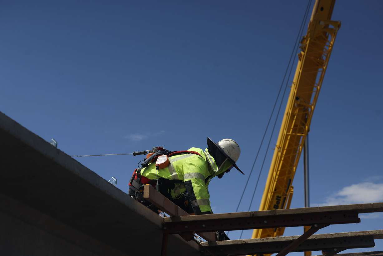 Amosta Brown wears a full brim hard hat sun visor to help keep cool as he works on the I-80 Renewed reconstruction project in Salt Lake City on Friday.