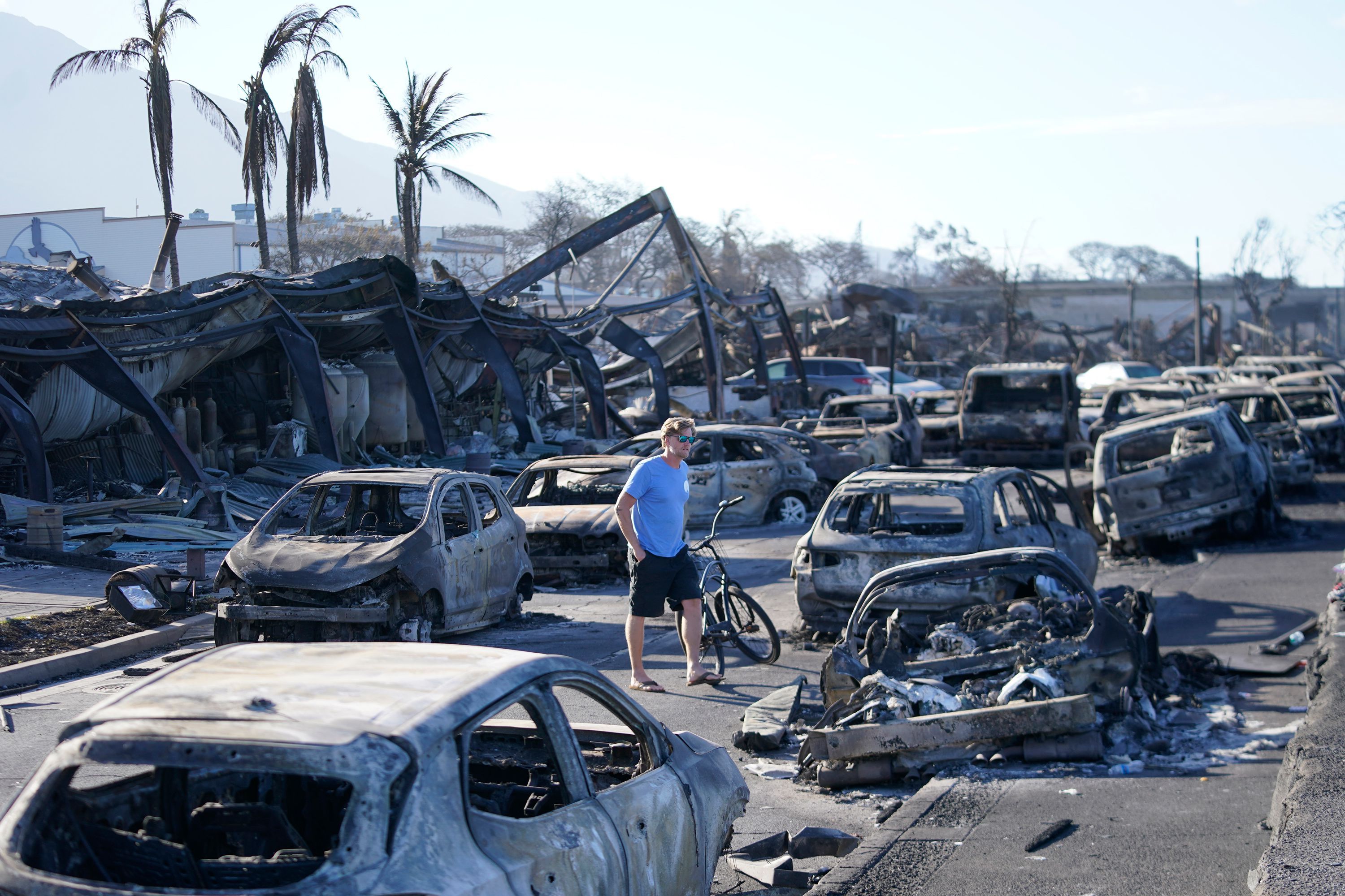 A man walks through wildfire wreckage on Friday in Lahaina, Hawaii. Officials estimated on Saturday that it will cost billions to restore the once-picturesque town of Lahaina.