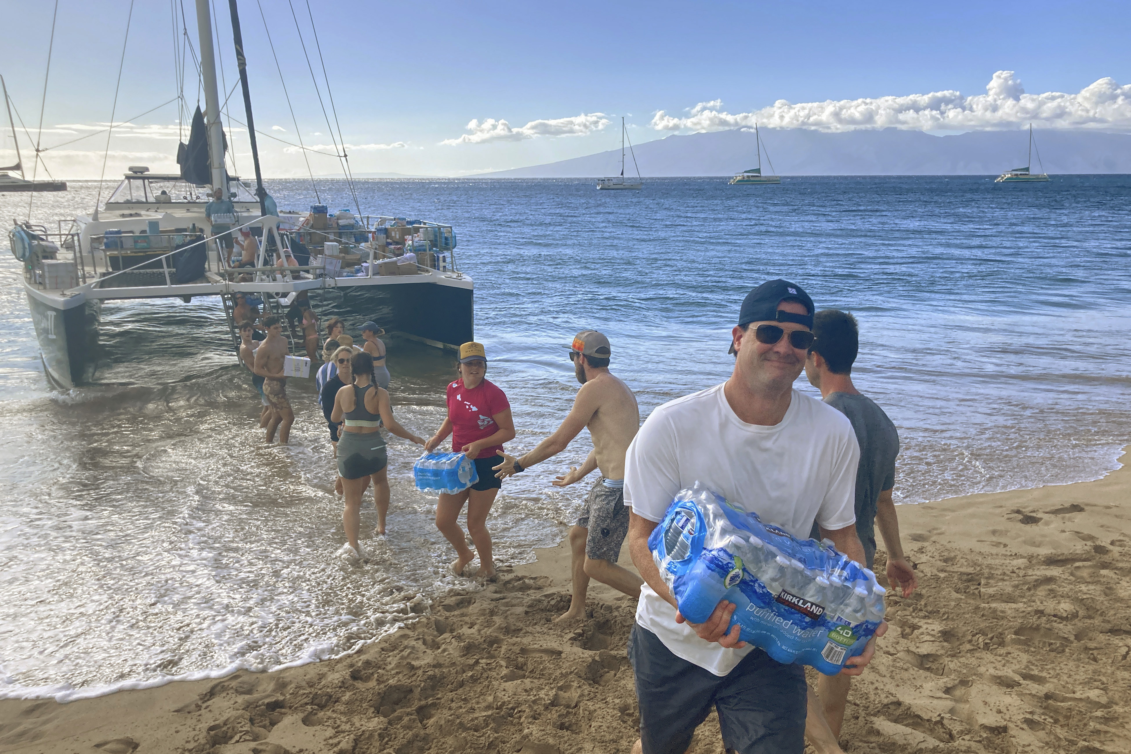 A group of volunteers who sailed from Maalaea Bay, Maui, form an assembly line on Kaanapali Beach on Saturday to unload donations from a boat. Residents have come together after a deadly fire destroyed hundreds of homes and left scores of people homeless.