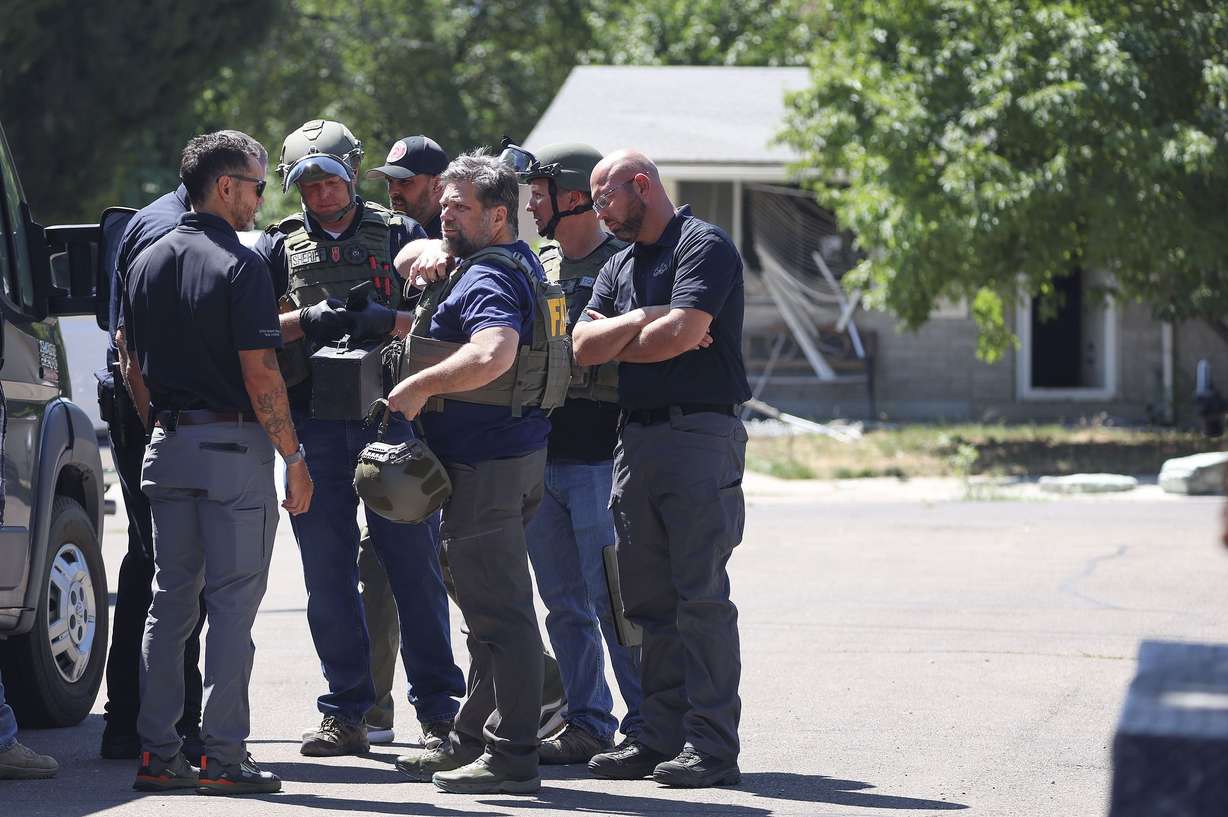 Law enforcement agents confer at the home of Craig Deeleuw Robertson who was shot and killed by FBI agents in Provo on Aug. 9. Robertson allegedly posted threatening comments about President Joe Biden hours before the president was scheduled to visit Utah.
