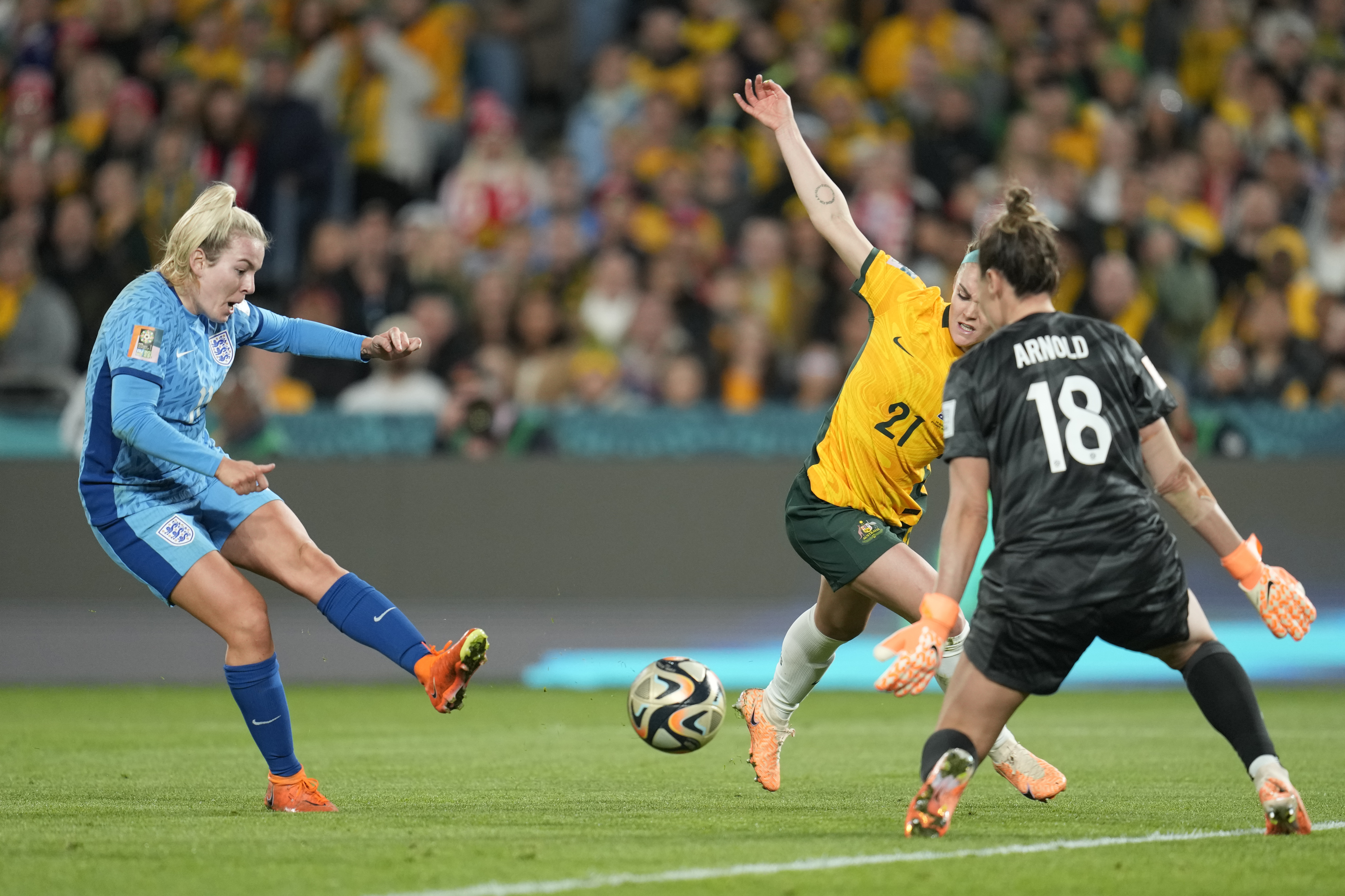 England's Lauren Hemp, left, scores her side's second goal past Australia's goalkeeper Mackenzie Arnold, as Australia's Ellie Carpenter, centre, tries to block during the Women's World Cup semifinal soccer match between Australia and England at Stadium Australia in Sydney, Australia, Wednesday, Aug. 16, 2023. 