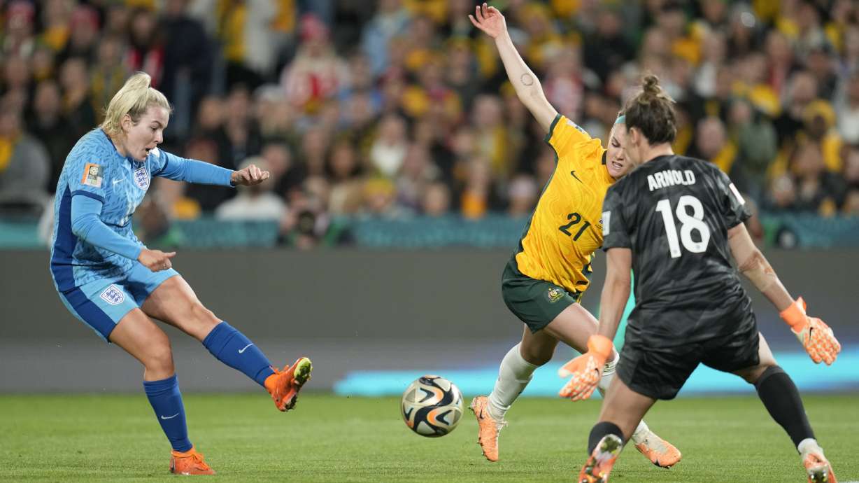 England's Lauren Hemp, left, scores her side's second goal past Australia's goalkeeper Mackenzie Arnold, as Australia's Ellie Carpenter, centre, tries to block during the Women's World Cup semifinal soccer match between Australia and England at Stadium Australia in Sydney, Australia, Wednesday, Aug. 16, 2023.