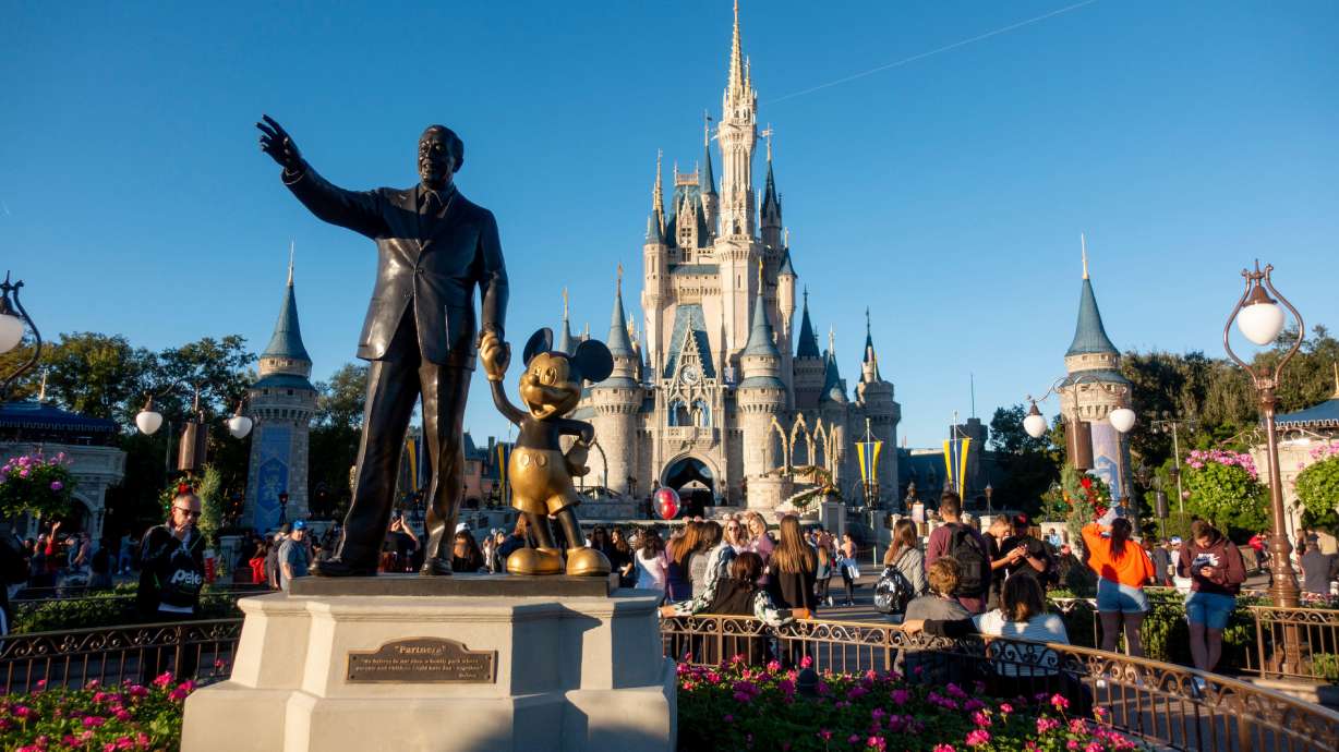 Walt Disney and Mickey Mouse statue are shown at Disney World in Orlando, Fla. Walt Disney Co said Wednesday it is raising some theme-park ticket prices for its Disneyland resort in California and Walt Disney World in Florida.