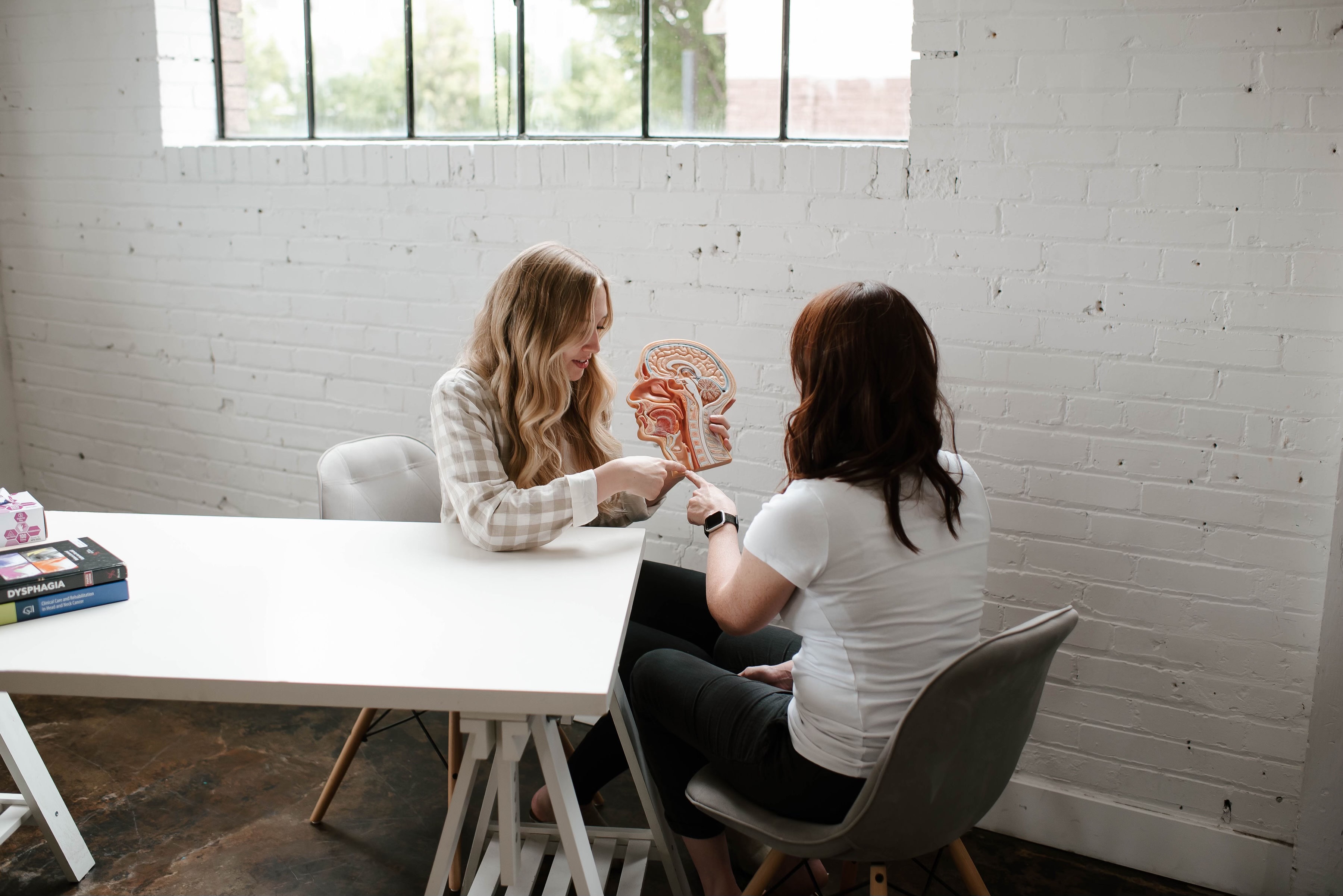 Summer Price shows her sister-in-law, Jamie Price, strategies to help clients learn how to speak at Middle Hill Speech and Voice Clinic in Draper.