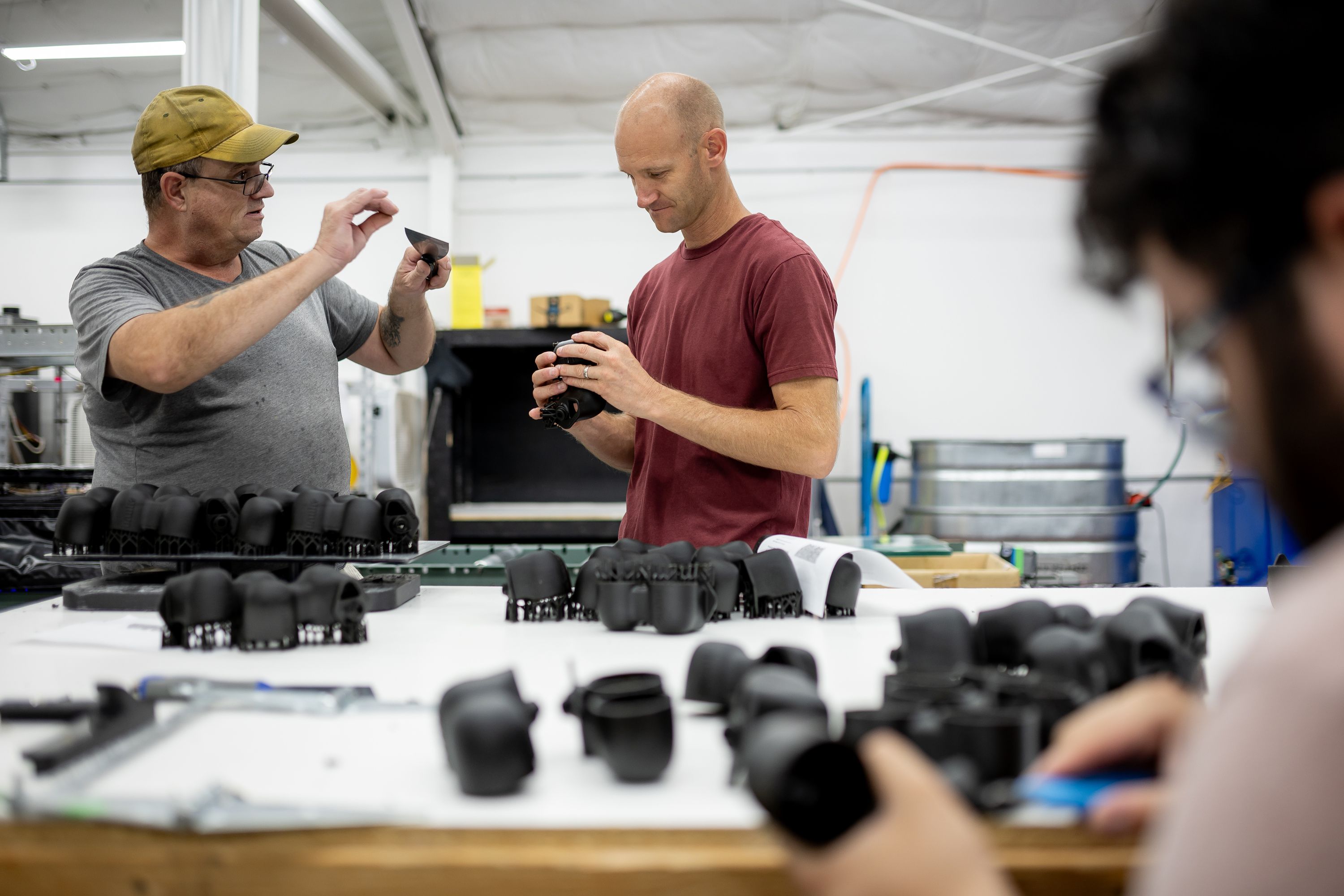 Merit3D CEO Spencer Loveless, center, talks to Jesse Drumm while he does finishing work on 3D-printed parts at the company’s manufacturing facility in Price on Thursday.