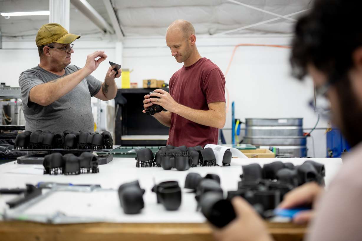 Merit3D CEO Spencer Loveless, center, talks to Jesse Drumm while he does finishing work on 3D-printed parts at the company’s manufacturing facility in Price on Thursday.