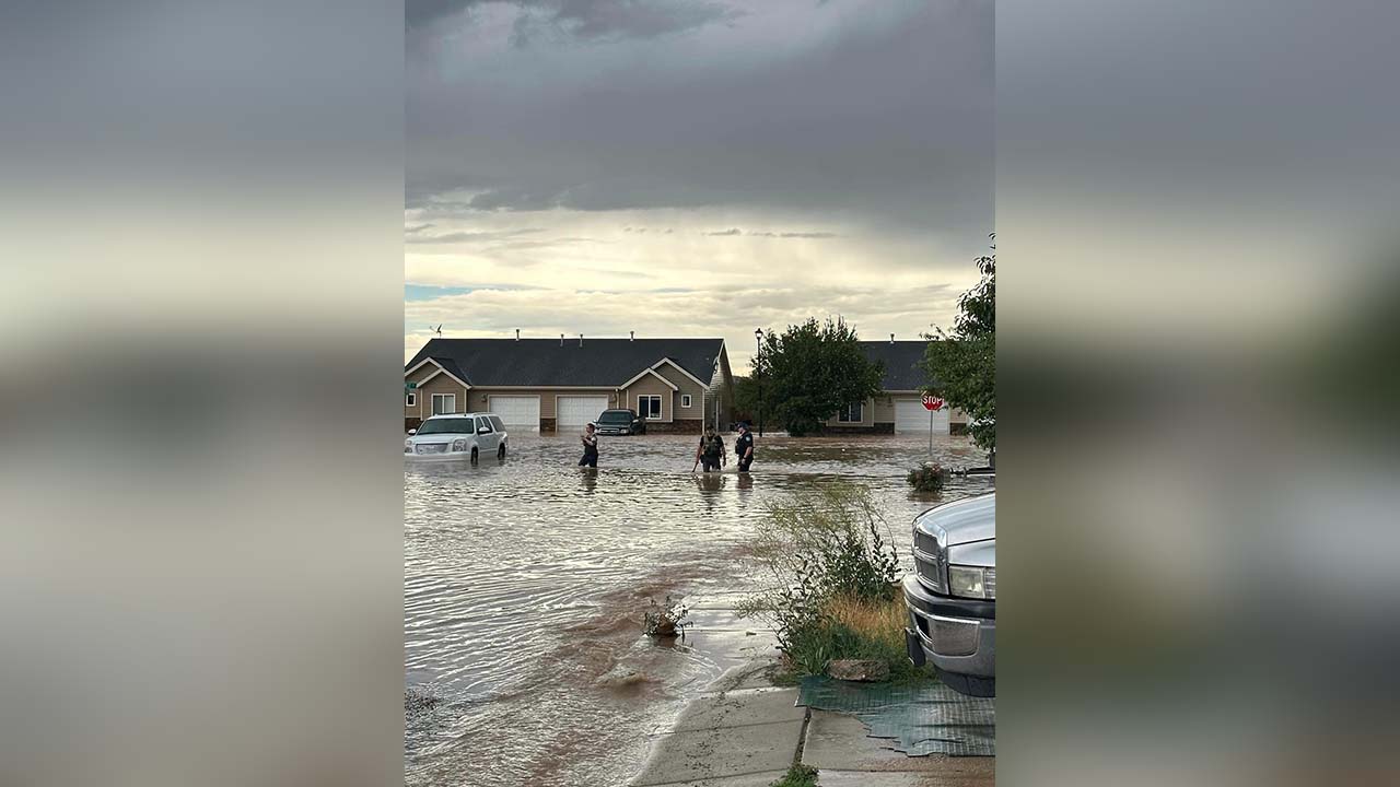 Law enforcement officers stand in the flood waters in a Cedar City neighborhood on Thursday. Heavy rain flooded streets, homes, a hospital and jail.