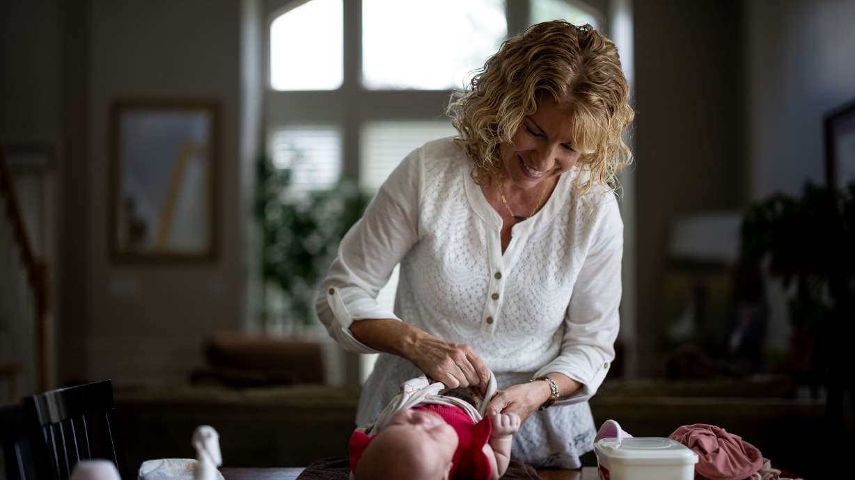 Cindy Davis unswaddles her 9-week-old granddaughter Indy while babysitting her at home in Cedar Hills on Tuesday. Grandparenting can boost grandkids’ sense of security and help grandparents live happier and longer lives, experts say.