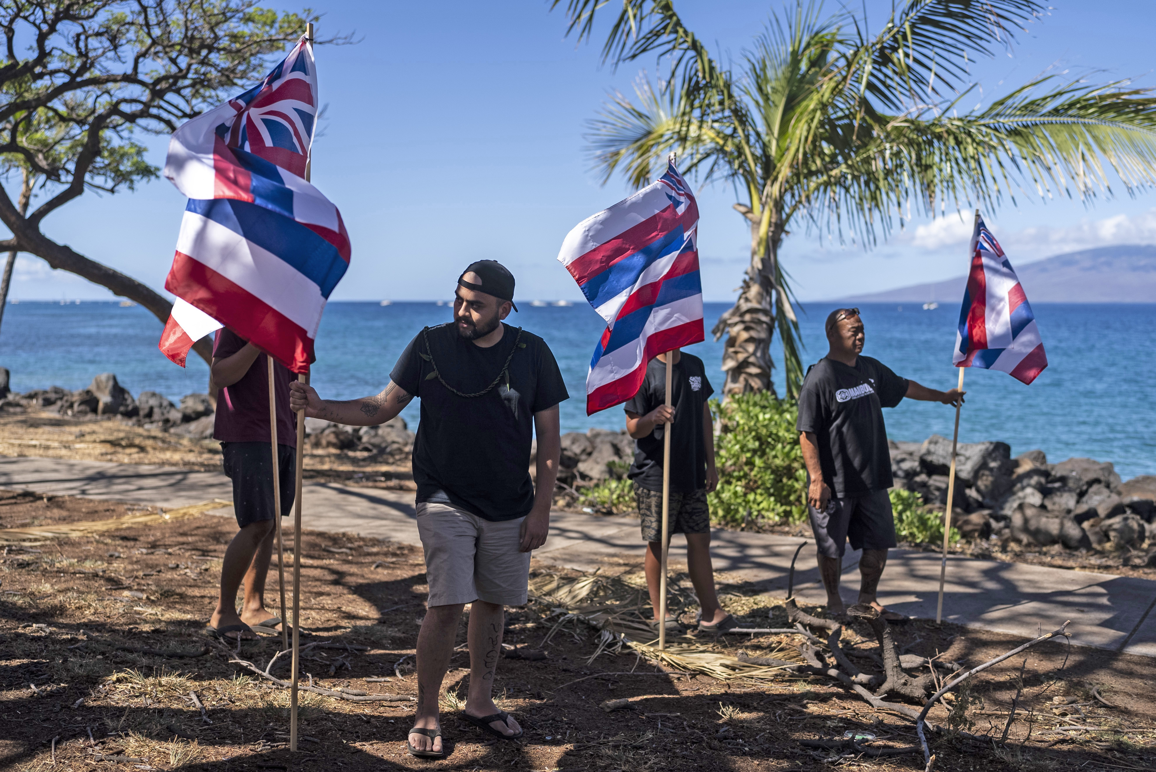 Community members hold Hawaiian flags during a news conference with Lahaina, Hawaii, residents affected by a deadly wildfire in Lahaina, Hawaii, Friday.