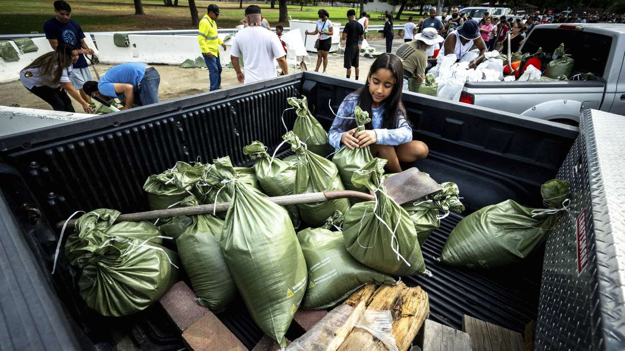 Madeline Noble, 9, sits in the back of her dad's pickup truck as she assists with sandbags at Wildwood Park in San Bernardino, Calif., on Saturday, as residents prepare for the arrival of Hurricane Hilary.