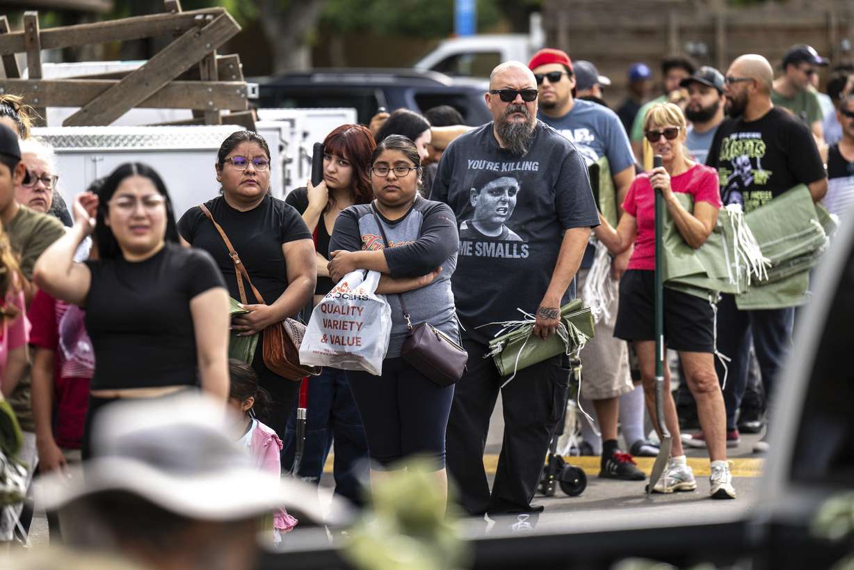 In an orderly queue, residents patiently wait with their shovels and sandbags at Wildwood Park in Saturday, San Bernardino, Calif.