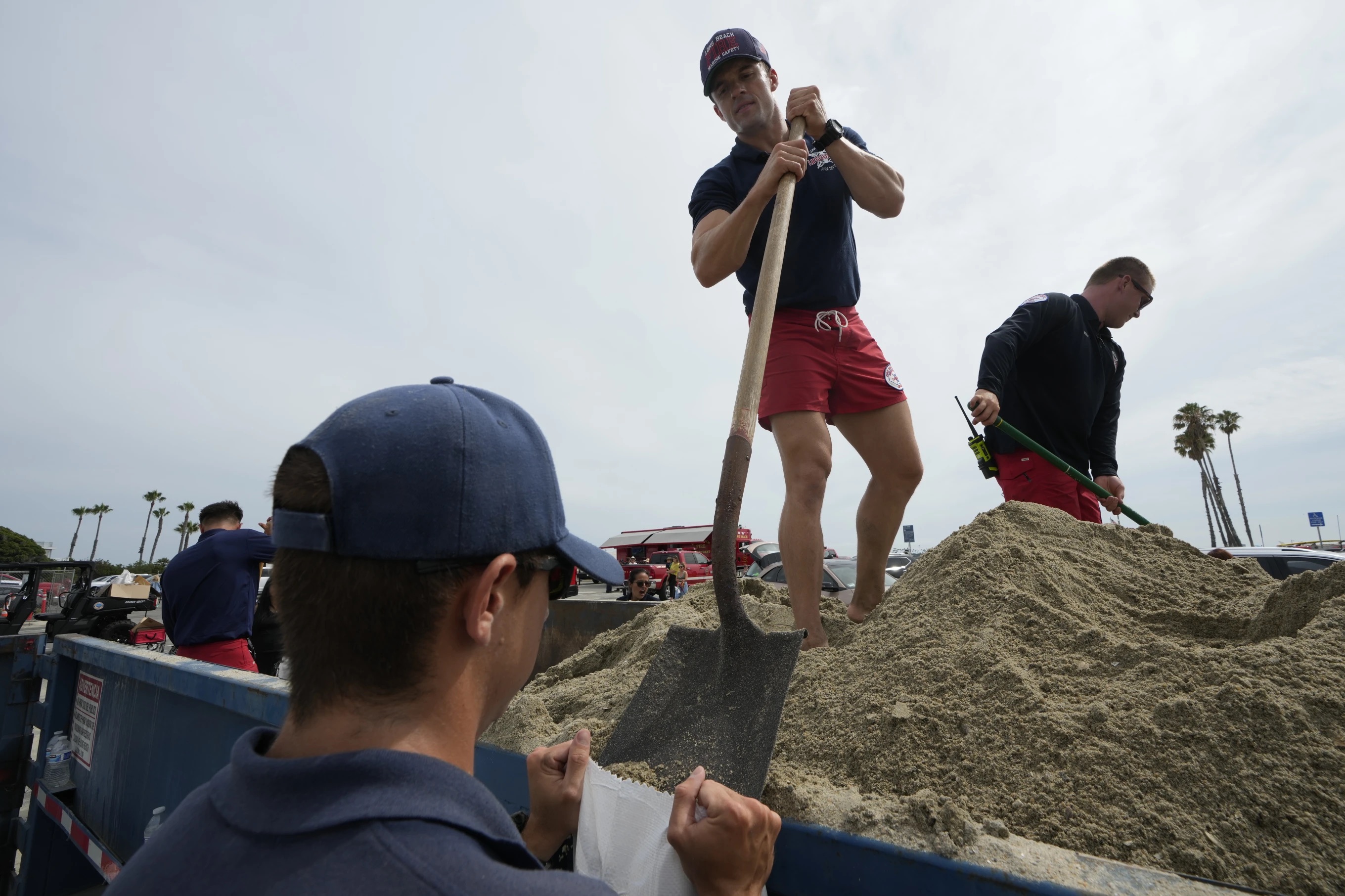 Long Beach lifeguards fill up sandbags for residents ahead of Hurricane Hilary, in Long Beach, Calif., Saturday.