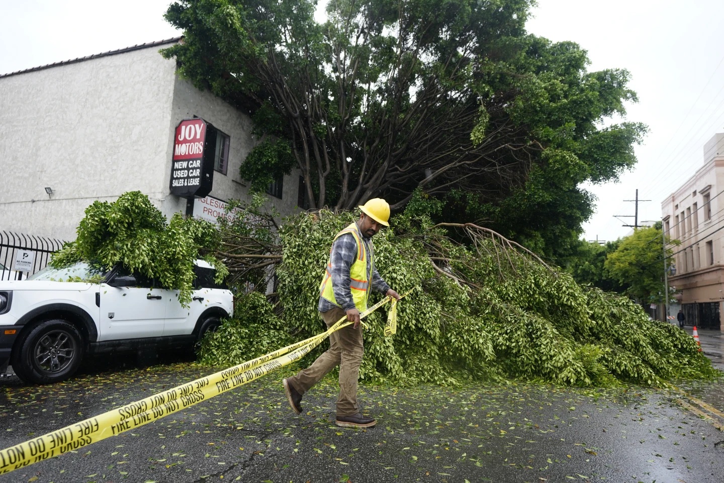 A worker drags caution tape to block off Pico Boulevard in Los Angeles on Sunday.