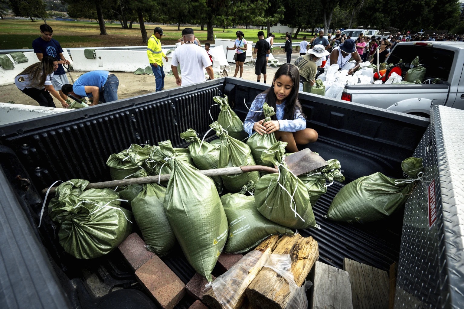 Madeline Noble, 9, sits in the back of her dad's pickup truck as she assists with sandbags at Wildwood Park in San Bernardino, Calif., on Saturday as residents prepare for the arrival of Hurricane Hilary.