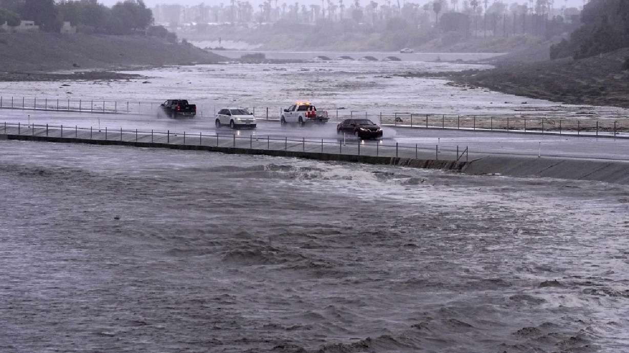 Vehicles cross over a flood control basin that has almost reached the street, Sunday in Palm Desert, Calif. Forecasters said Tropical Storm Hilary was the first tropical storm to hit Southern California in 84 years.