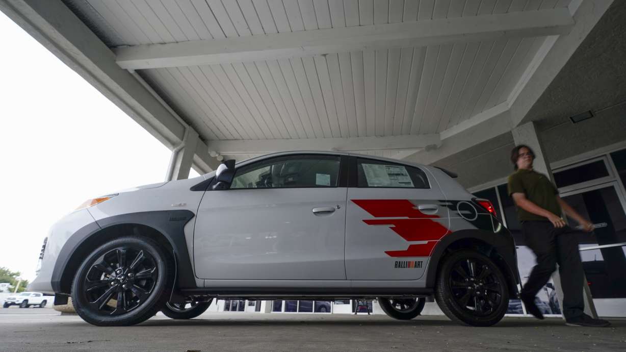 A Mitsubishi salesman walks past a new Mitsubishi Mirage on Aug. 8, in El Cajon, Calif. The Mirage remains the lone new vehicle whose average sale price is under $20,000.