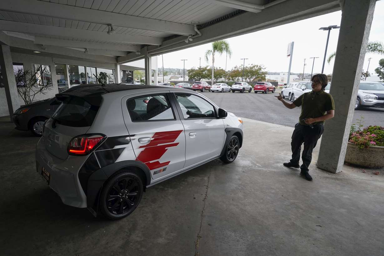 Mitsubishi salesman Matthew Boston points to a new Mitsubishi Mirage for sale at El Cajon Mitsubishi Aug. 8, in El Cajon, Calif. At a time when auto buyers increasingly want pricey SUVs and trucks and fewer want small cars, the Mirage remains the lone new vehicle whose average sale price is under 20 grand.