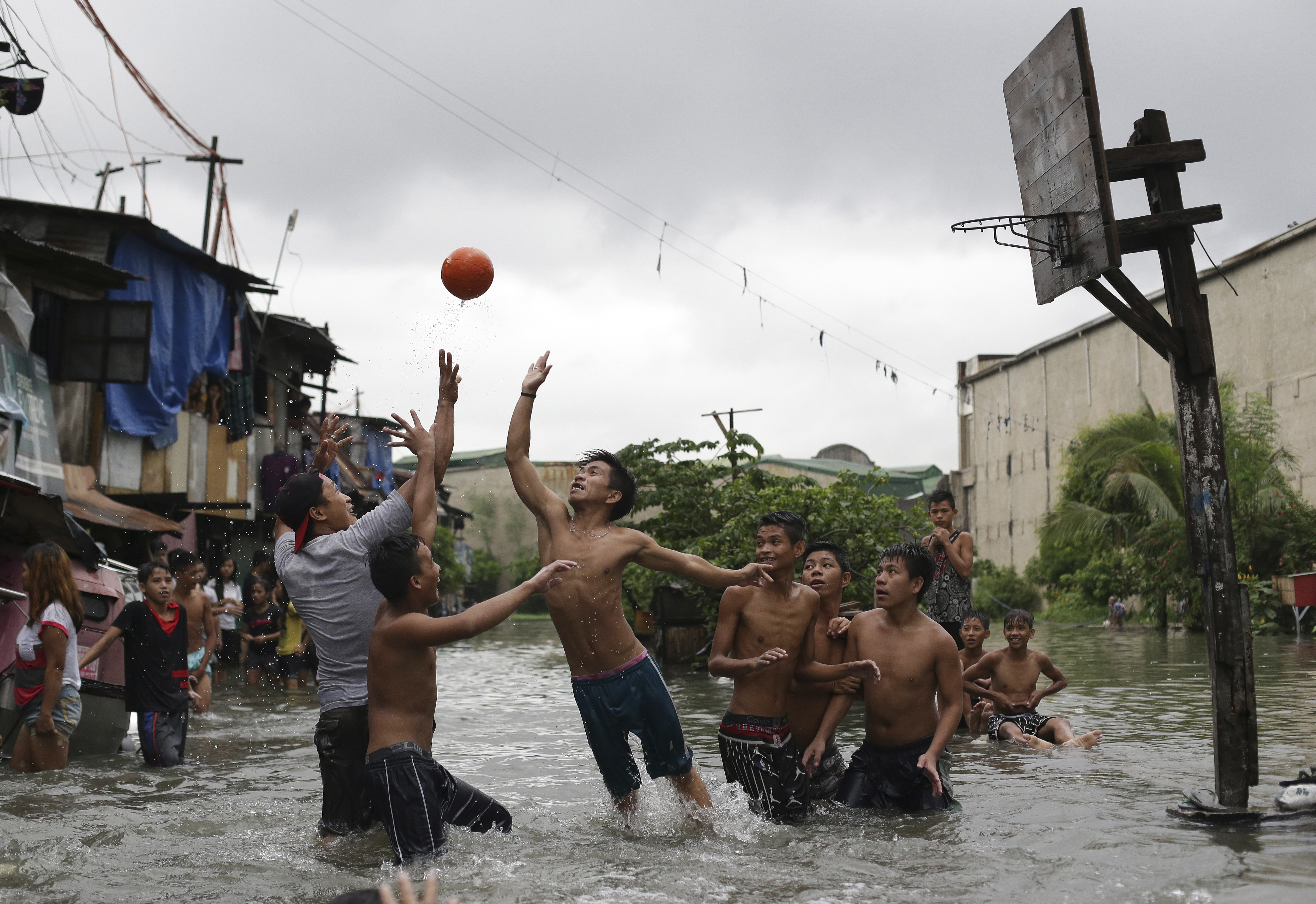 FILE - Filipino boys play basketball in floodwaters from a swollen creek at a coastal village in Malabon, north of Manila, Philippines, Wednesday, July 8, 2015. 