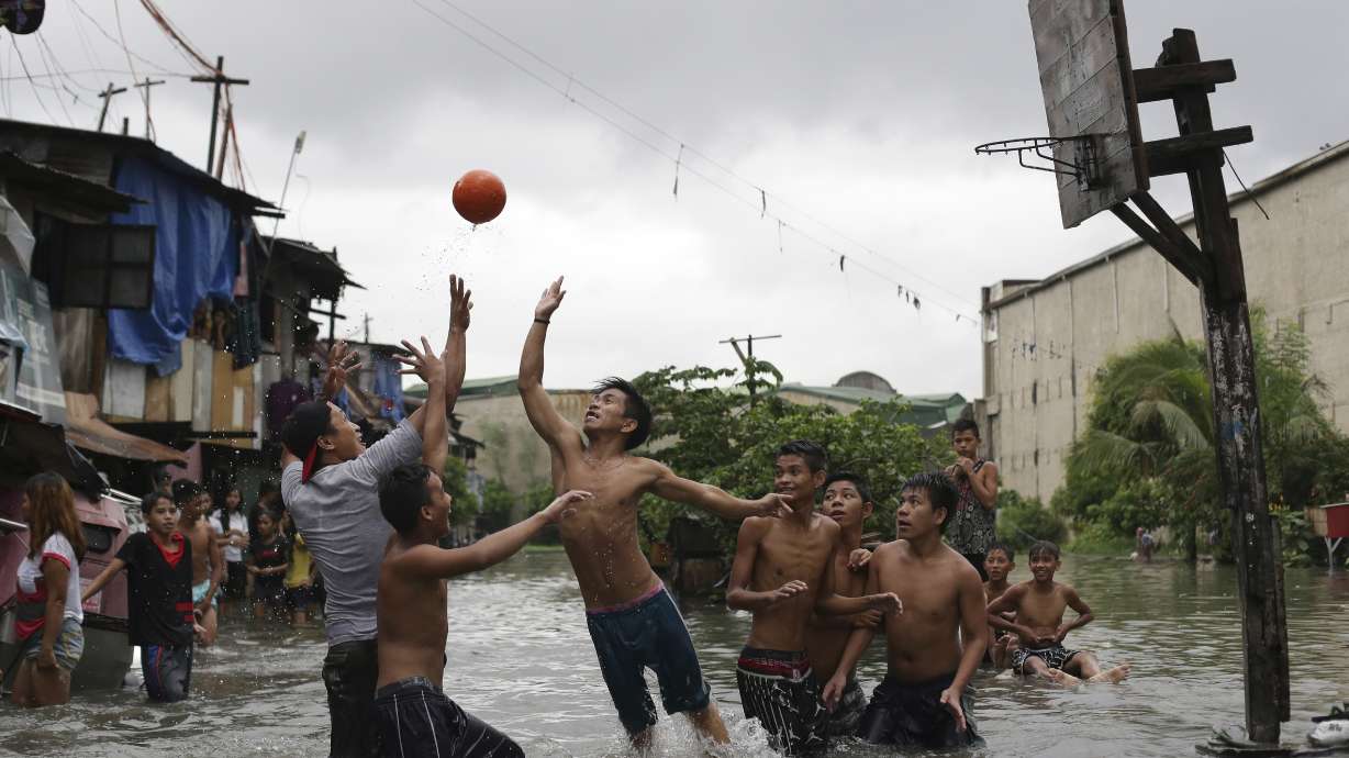 FILE - Filipino boys play basketball in floodwaters from a swollen creek at a coastal village in Malabon, north of Manila, Philippines, Wednesday, July 8, 2015.