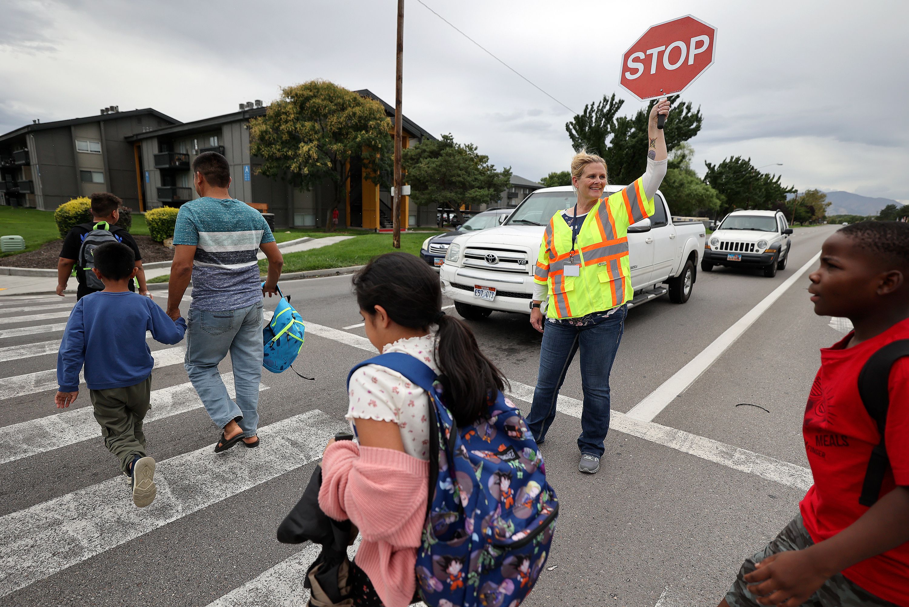 Unified police crossing guard April McCoy escorts people across 3900 South at 700 West on the border of South Salt Lake and Millcreek on Monday. Salt Lake City is looking to fill vacant crossing guard positions and is offering $17 an hour plus a $250 signing bonus.