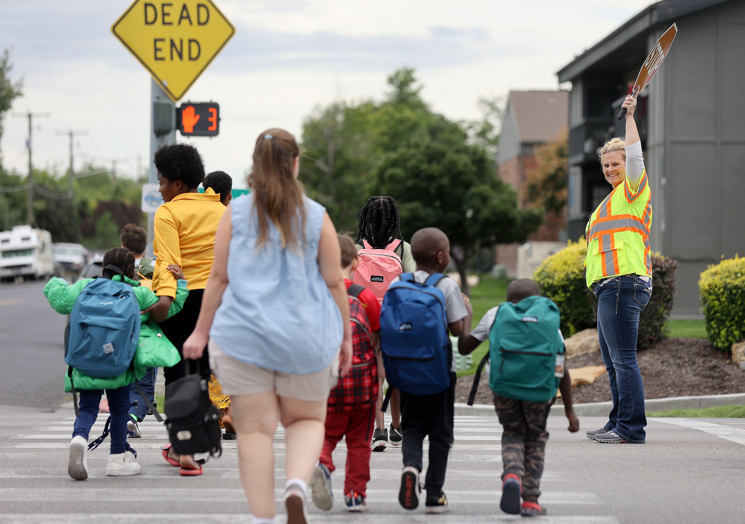 Unified police crossing guard April McCoy escorts people across 3900 South at 700 West on the border of South Salt Lake and Millcreek on Monday. Salt Lake City is looking to fill vacant crossing guard positions and is offering $17 an hour plus a $250 signing bonus.