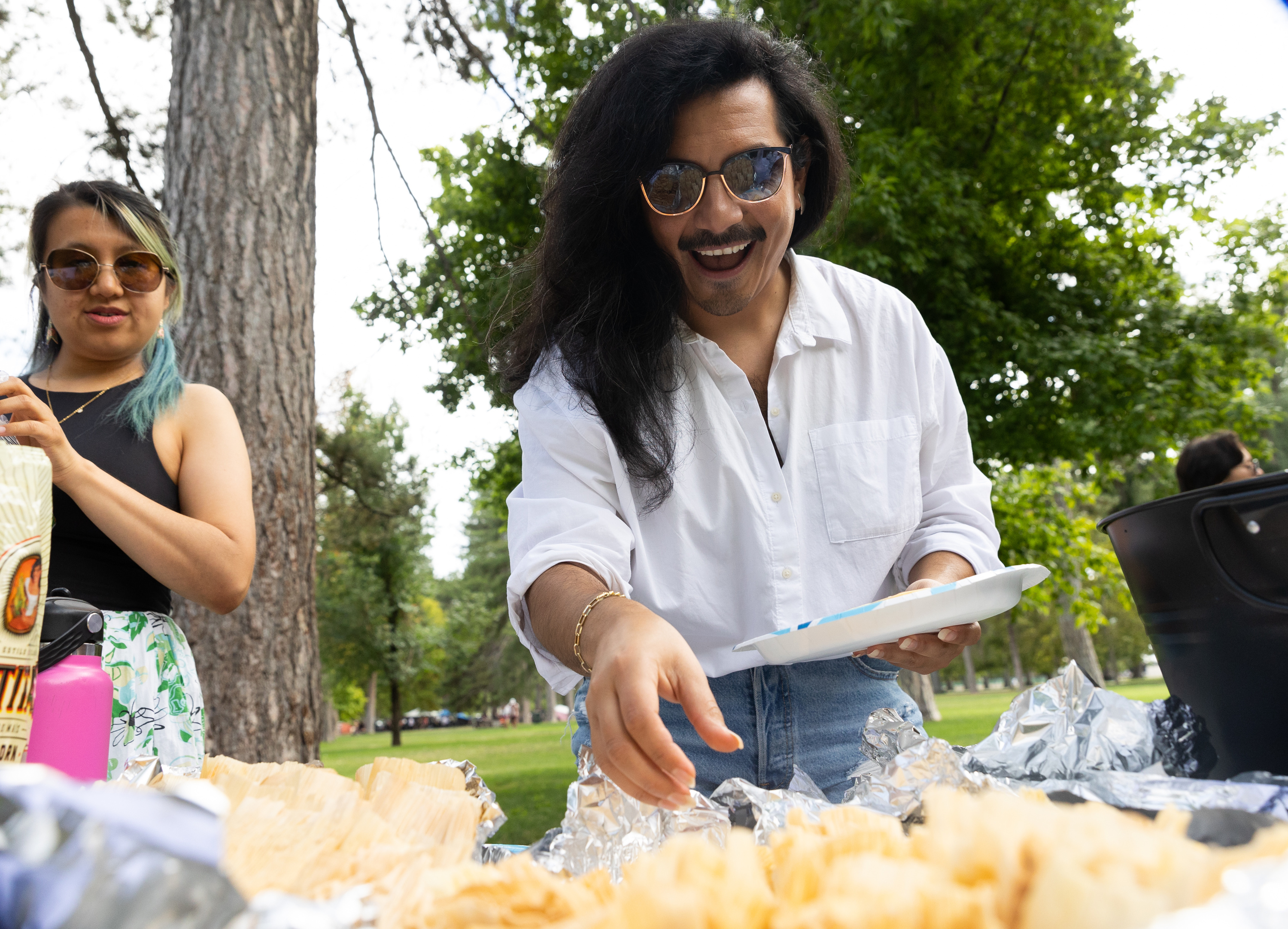Andres Brown grabs a tamale at an event celebrating the two-year anniversary of Unidxs at Liberty Park on Aug. 20.