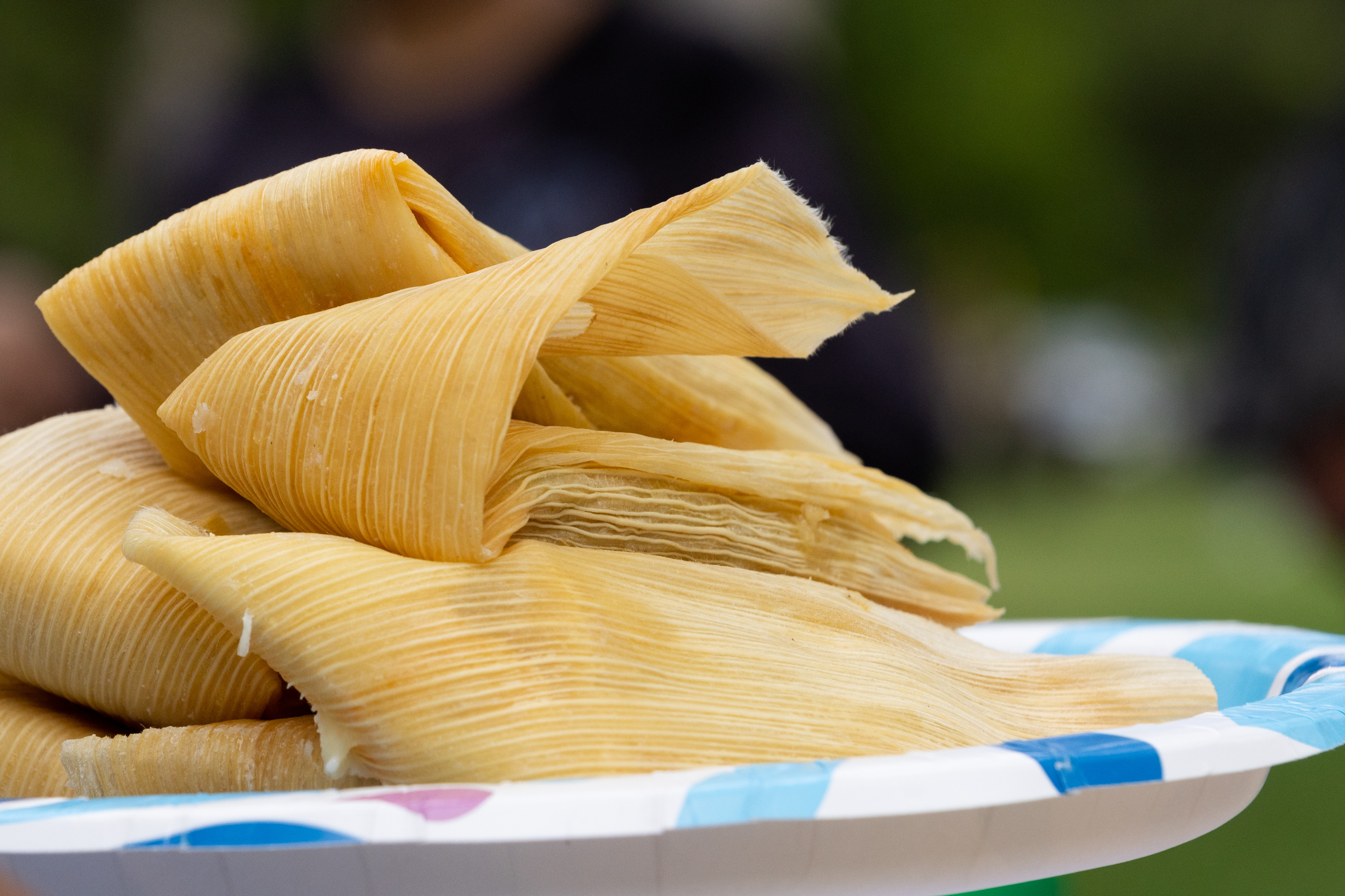 Alan Castillo stacks tamales on a plate at an event celebrating the two-year anniversary of Unidxs.