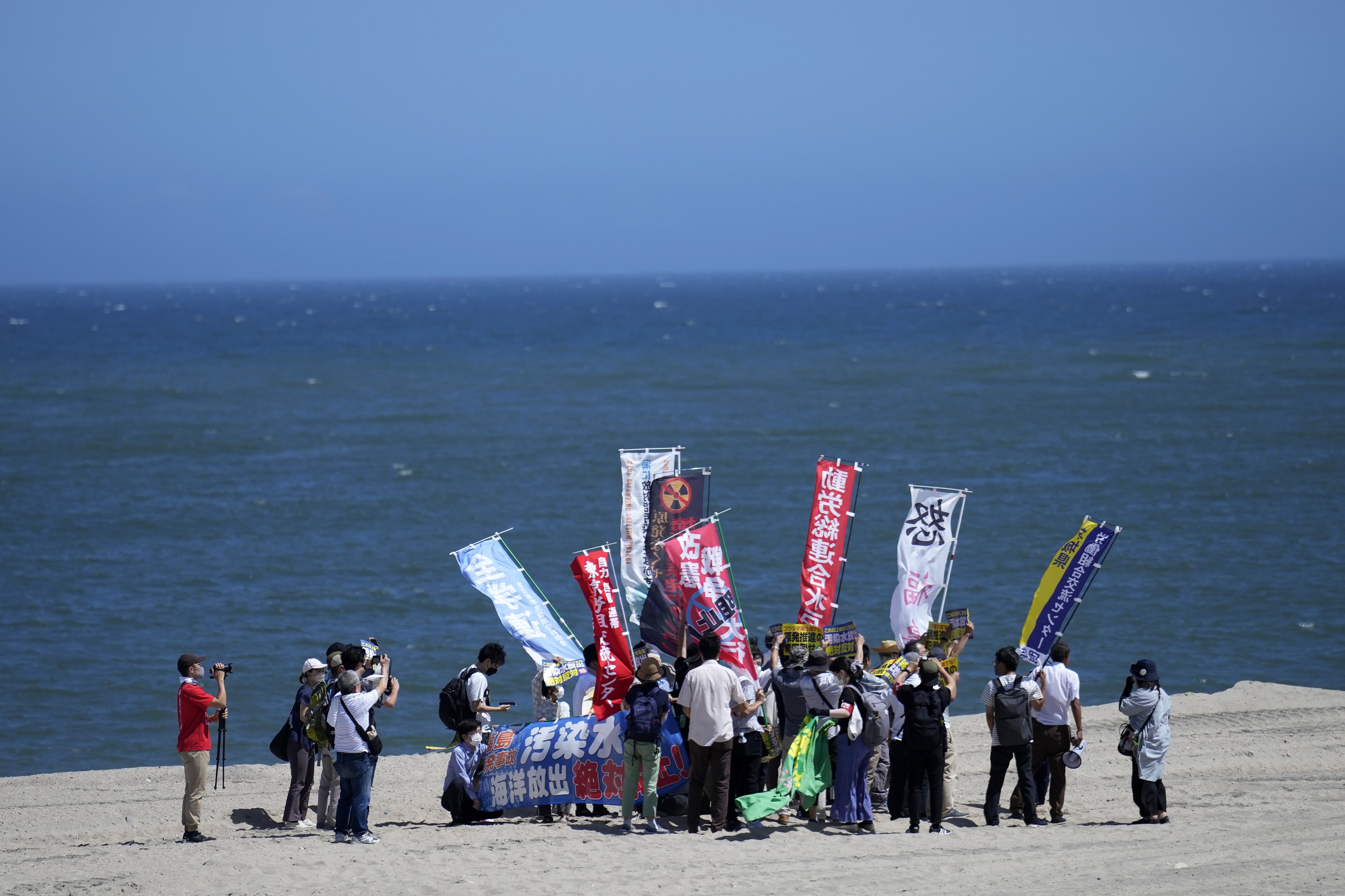 People protest at a beach toward the Fukushima Daiichi nuclear power plant, damaged by a massive March 11, 2011, earthquake and tsunami, in Namie town, northeastern Japan, Thursday. The plant says it began releasing its first batch of treated radioactive water into the Pacific Ocean on Thursday.